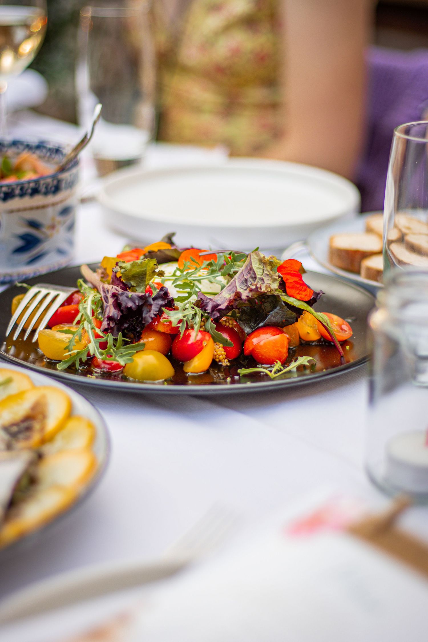 Scherp detail van een bord met tomaatjes en gerecht op een wit tafelkleed, onderdeel van een feestelijke 21-diner.