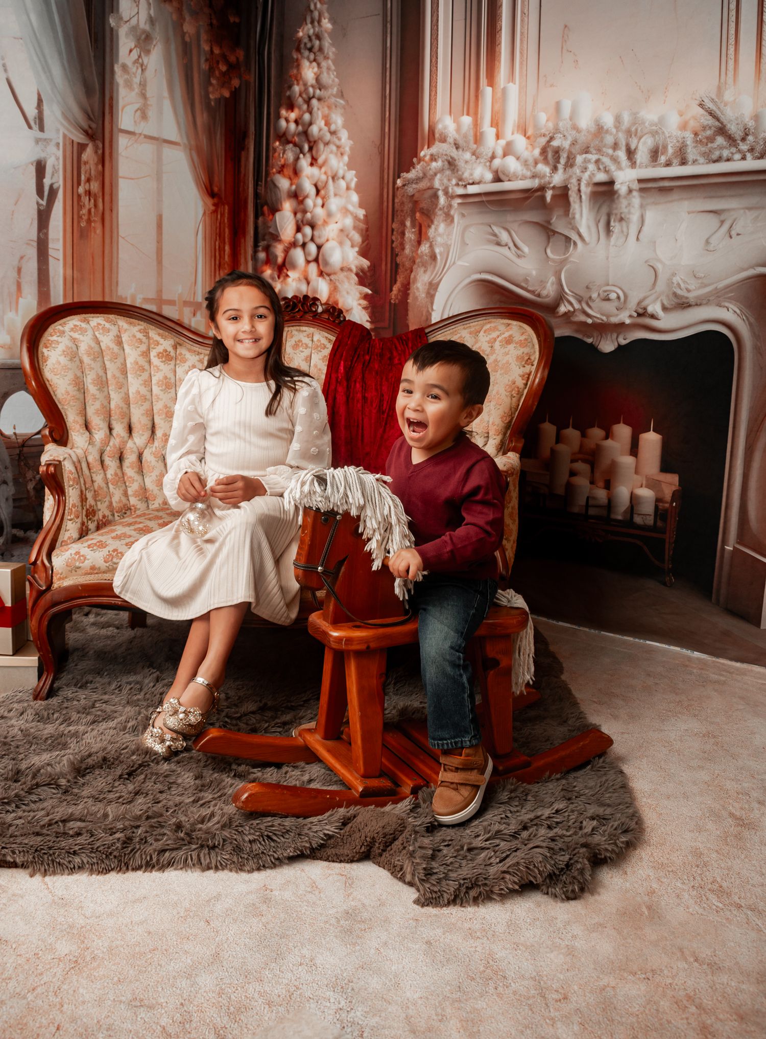 Children sitting on vintage sofa near decorated Christmas fireplace in elegant holiday setting.