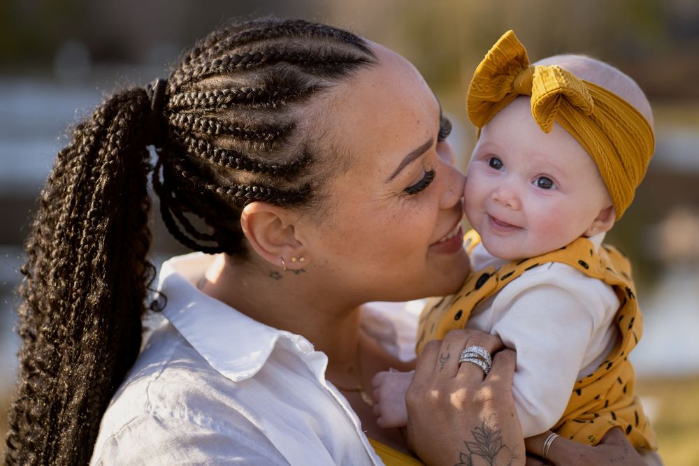 An intimate portrait showing affection between two people wearing white and yellow clothing outdoors.