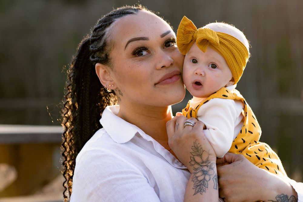 A tender moment captured between two people in white clothing with yellow accents against a natural background.