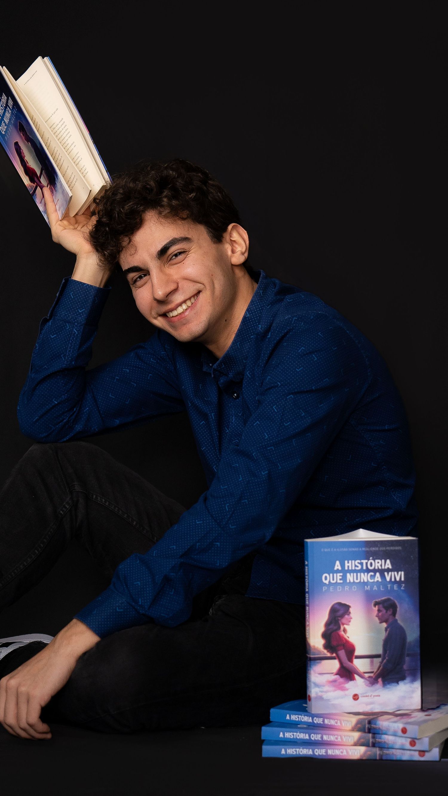 Person posing with book titled 'A Historia Que Nunca Vivi' in studio setting.