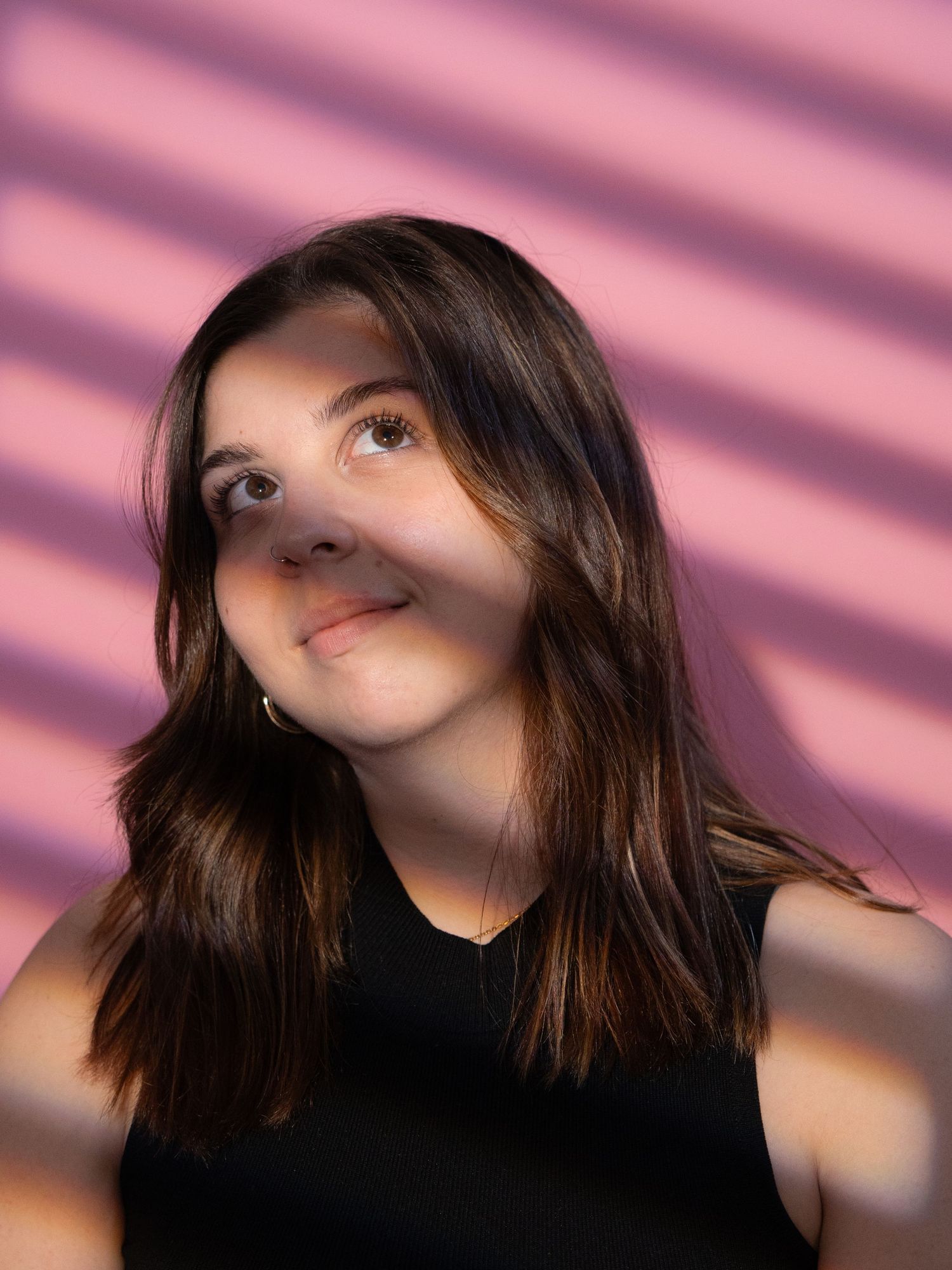 A portrait with dramatic pink lighting and shadows creating a moody aesthetic.