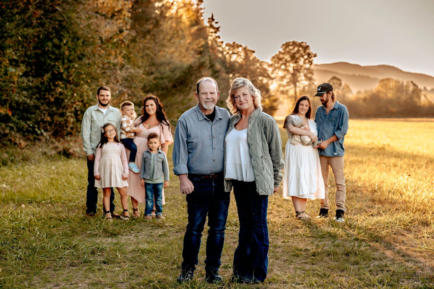 Family portrait session in a golden field at sunset with mountains in the background.