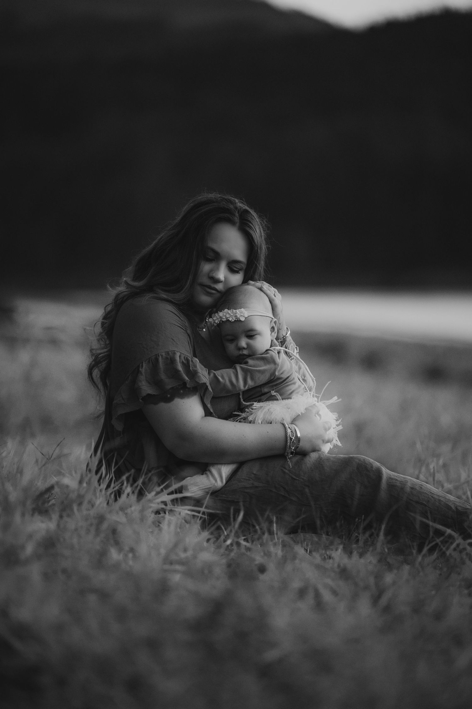 Black and white portrait series showing tender moments in a grassy field.