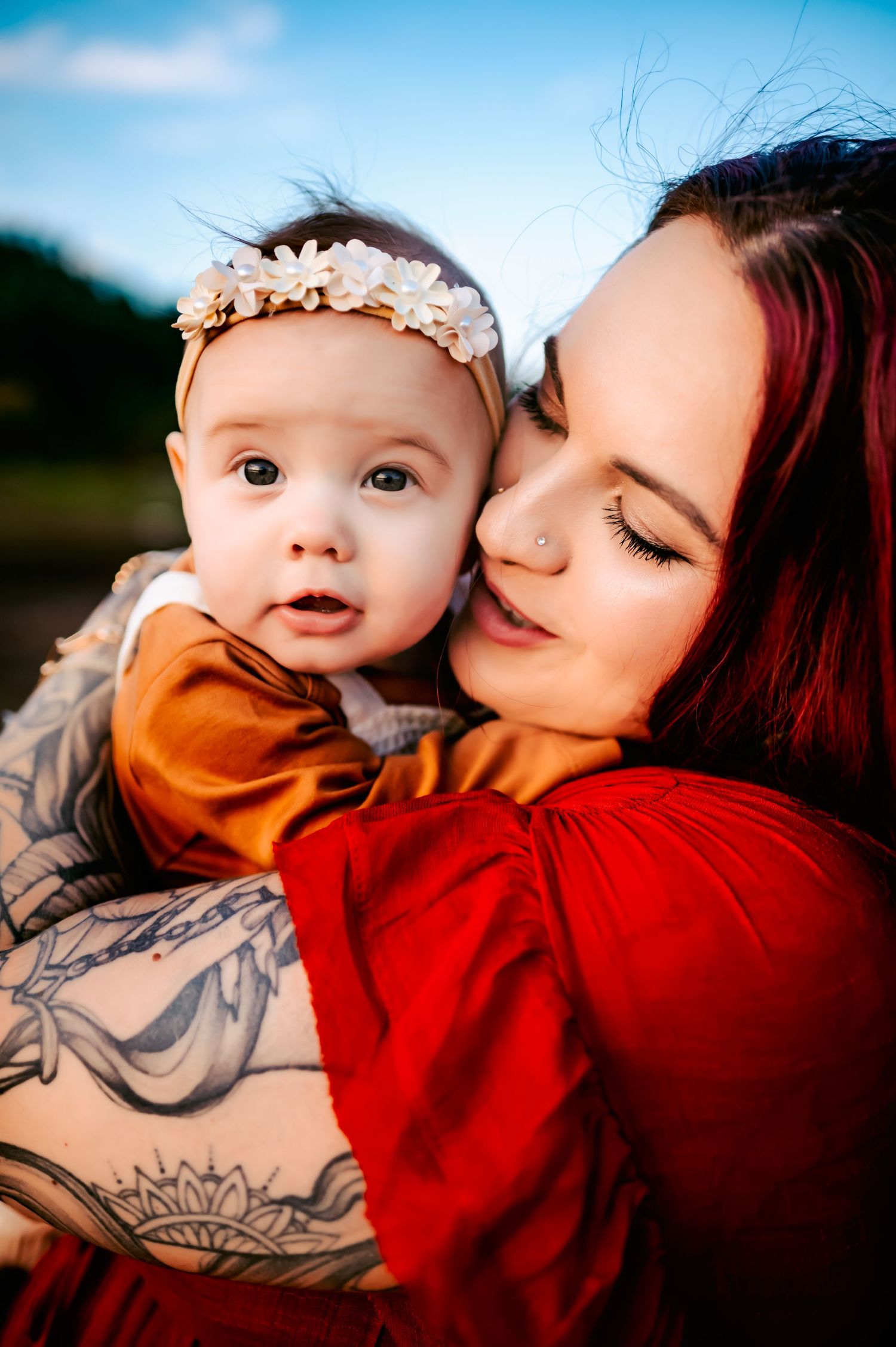 Artistic portraits featuring vibrant red clothing and visible tattoo art against blue sky.