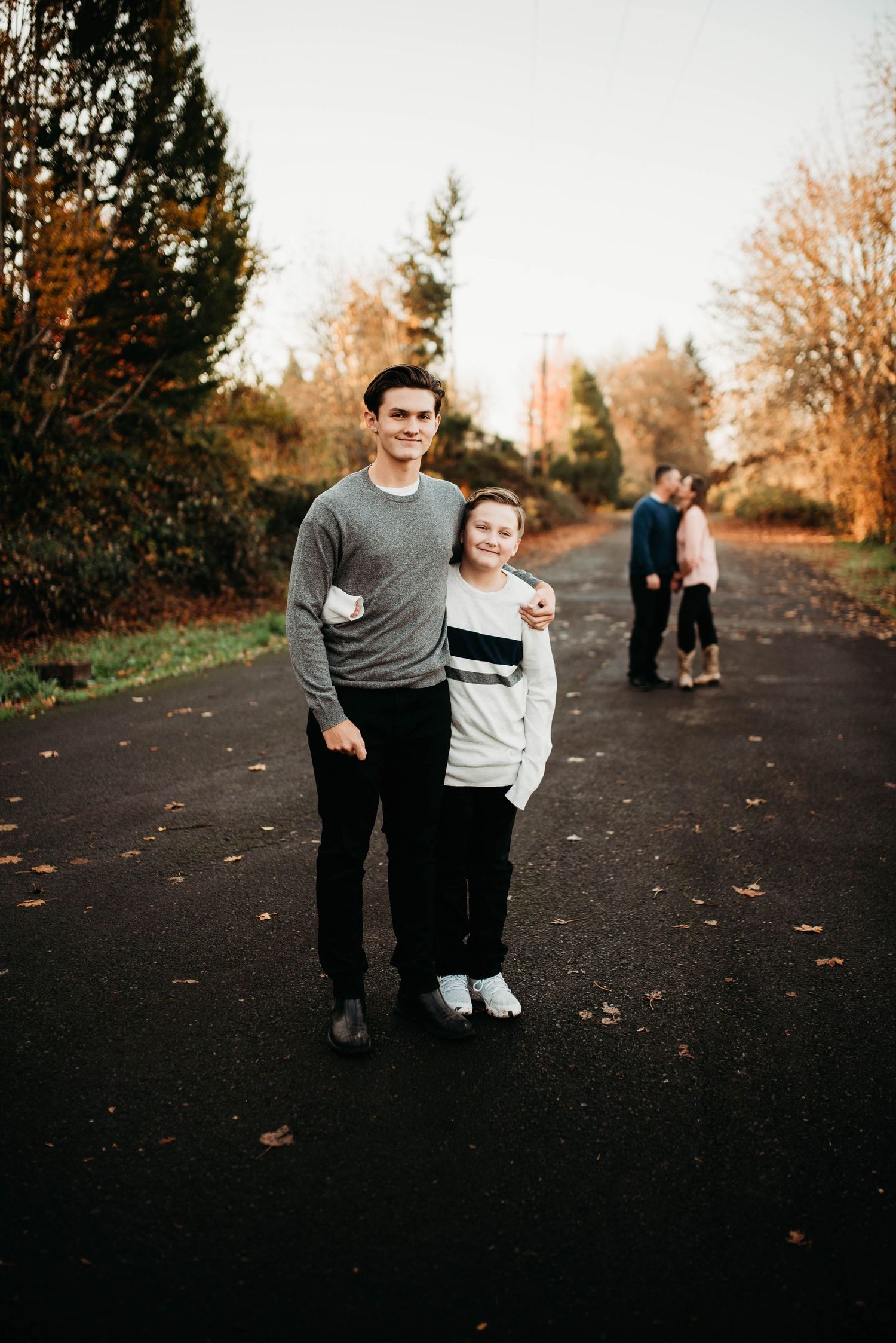 A family walking together on a dark path with trees in the background during golden hour.