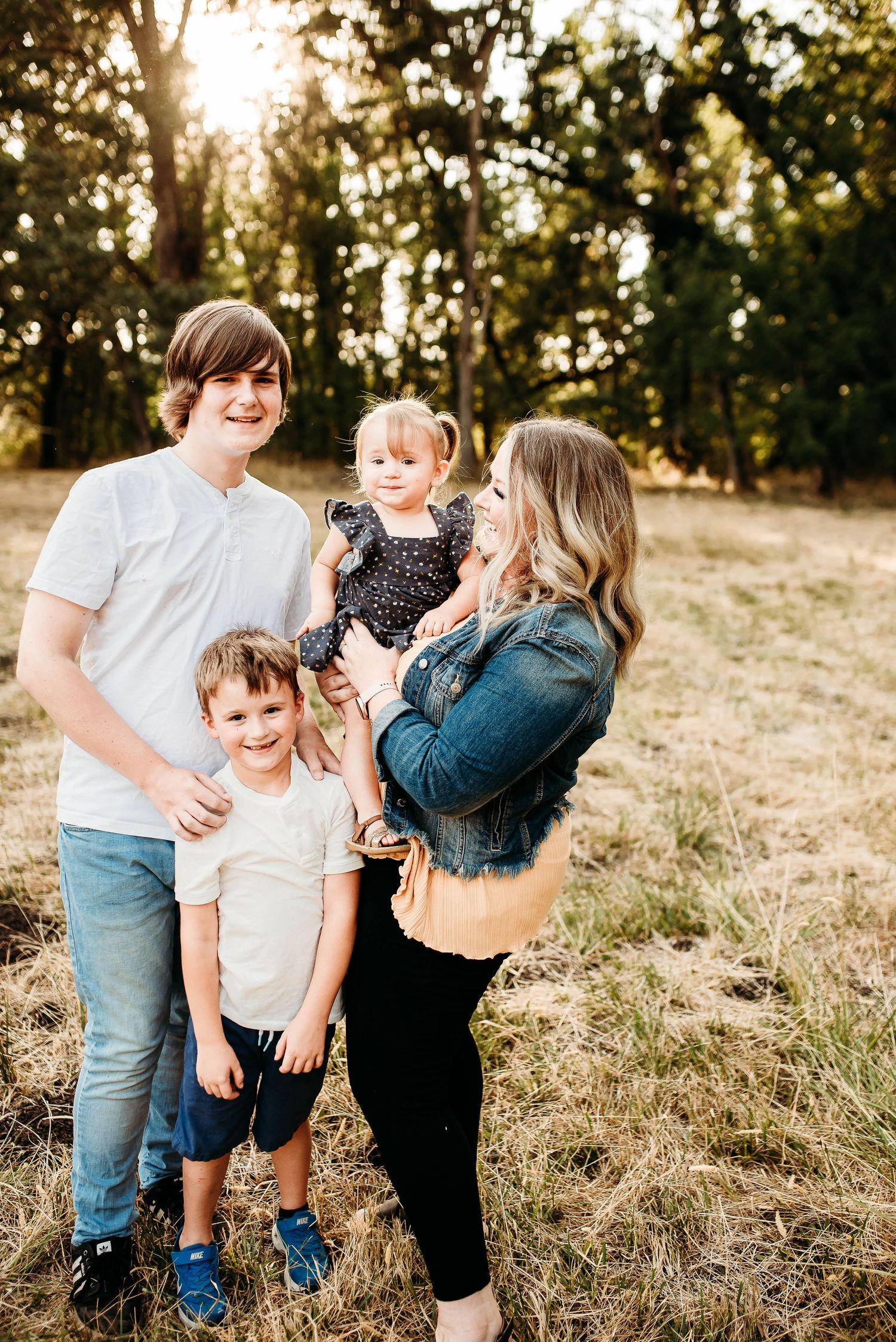 Candid family moments captured in warm evening light among tall grass.