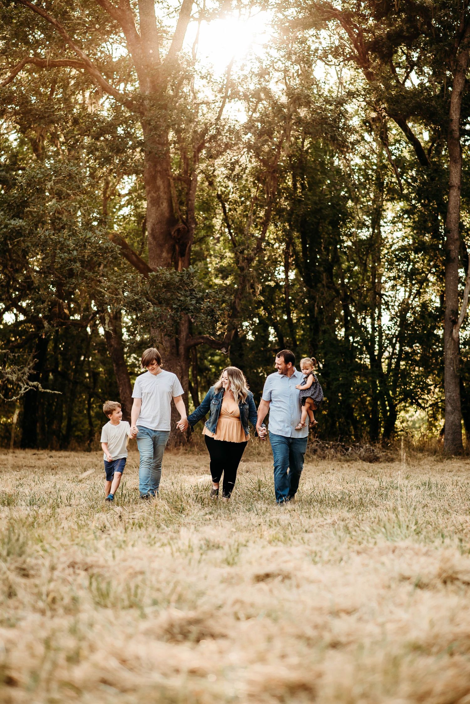 People strolling together through a sun-dappled field at dusk.