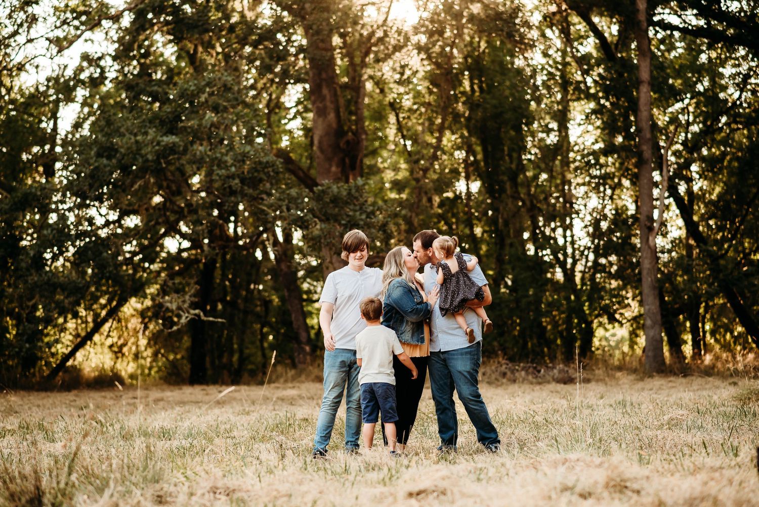 Group walking through sunlit meadow during golden hour photo session.