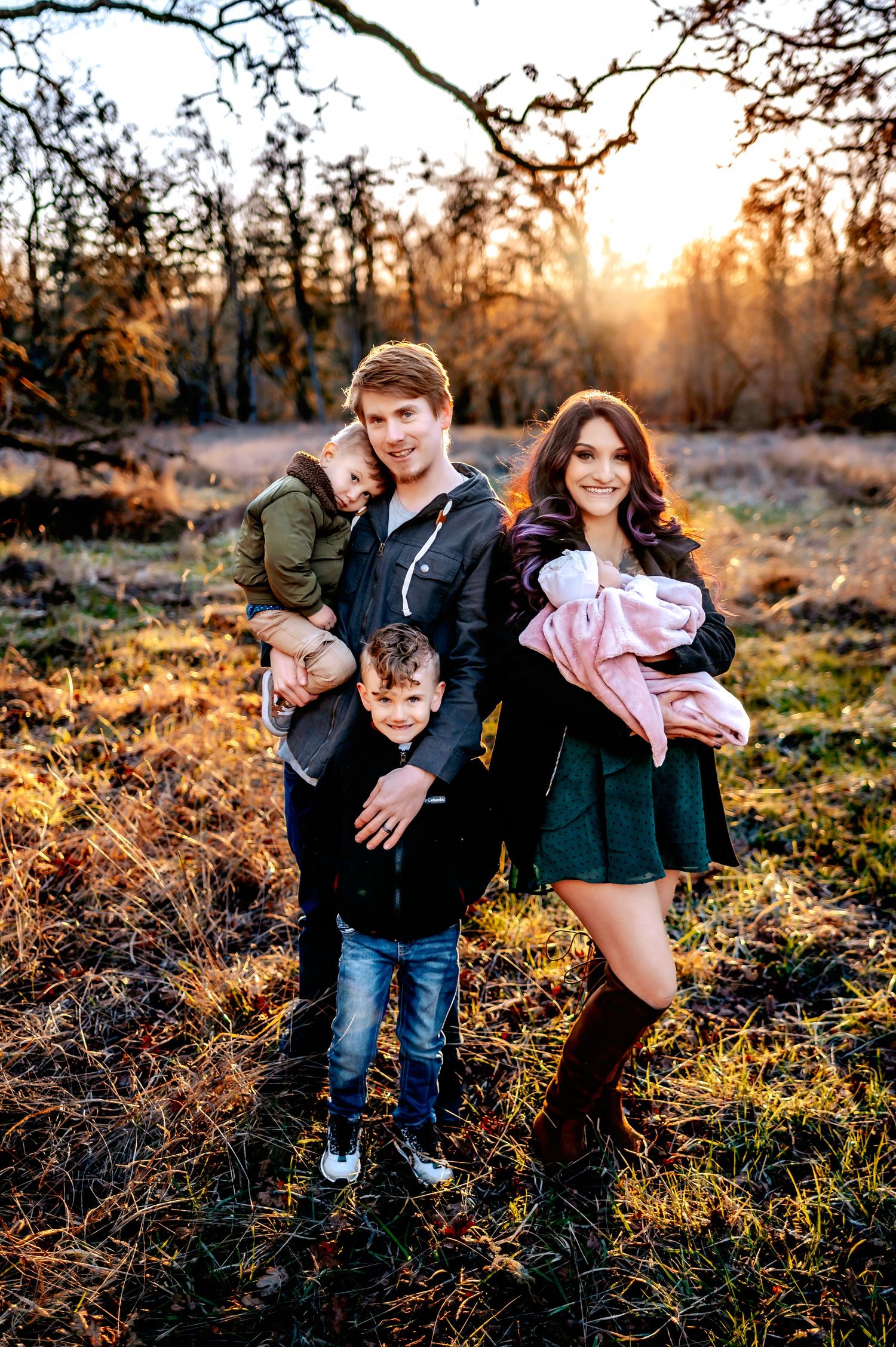 Family enjoying playful moments together in a sunlit autumn field.