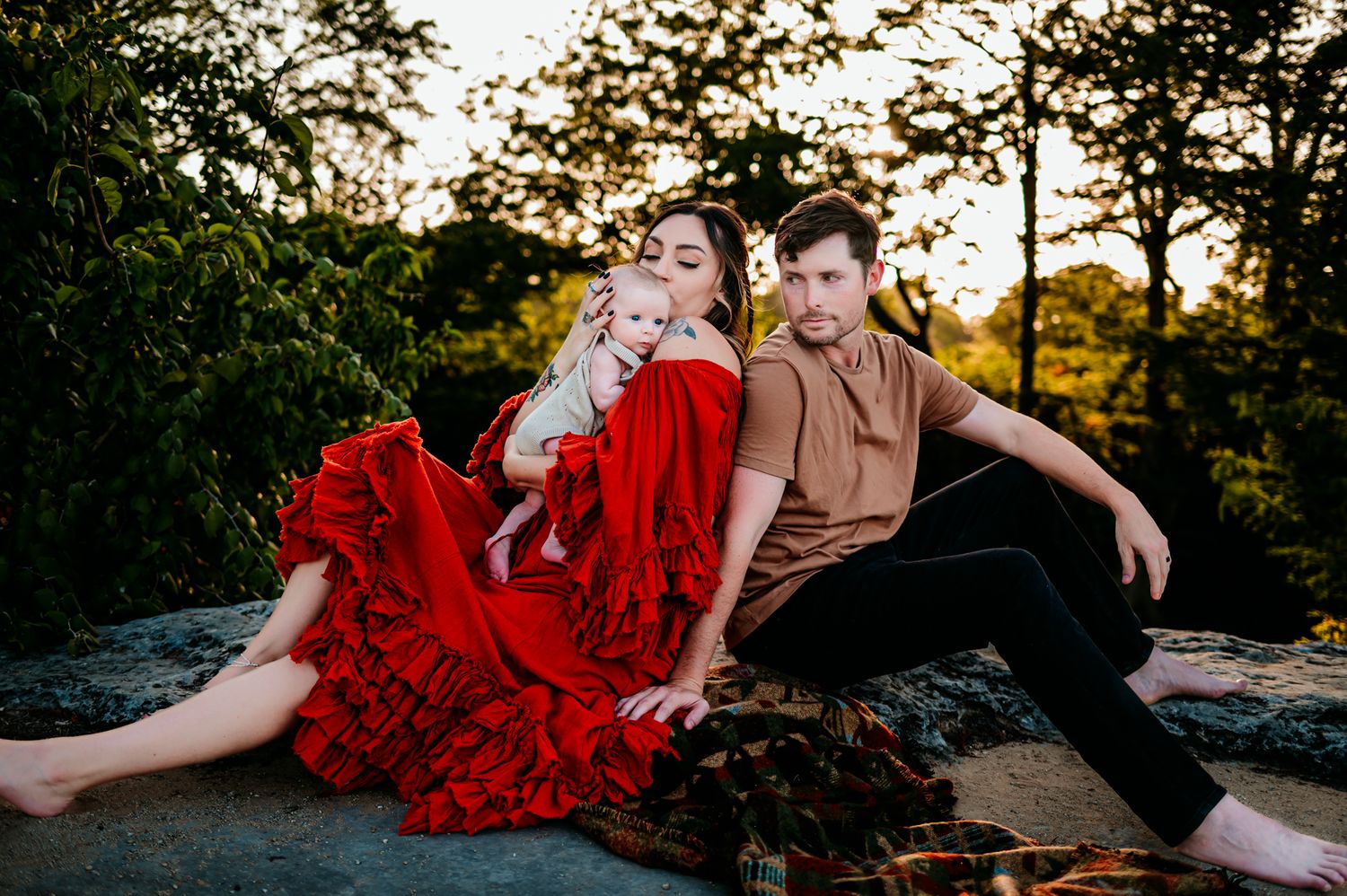 Candid family moments captured on rocky outcrop with lush greenery in background.