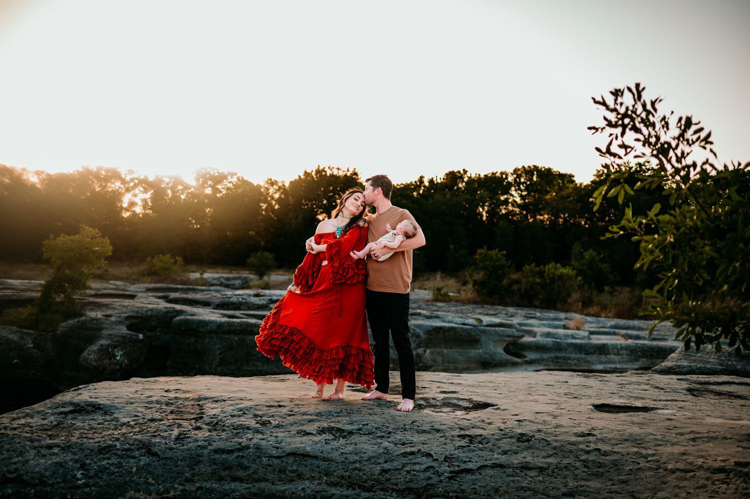 Family photoshoot on rocky terrain during golden hour with dramatic landscape views.