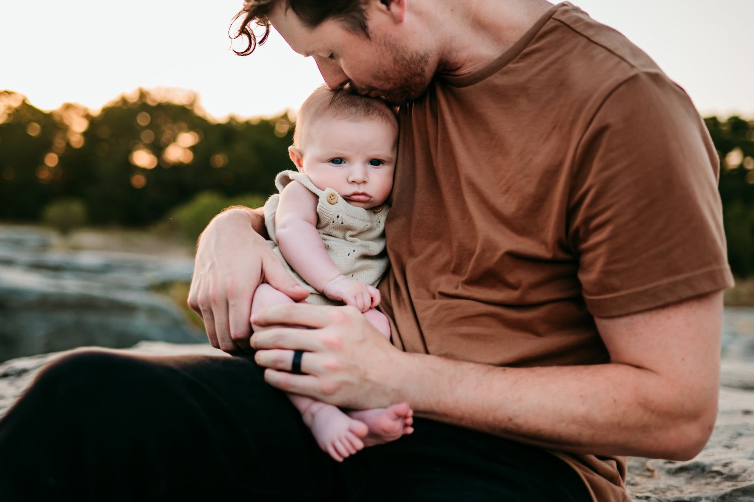 Intimate family moment captured in soft lighting against white background.