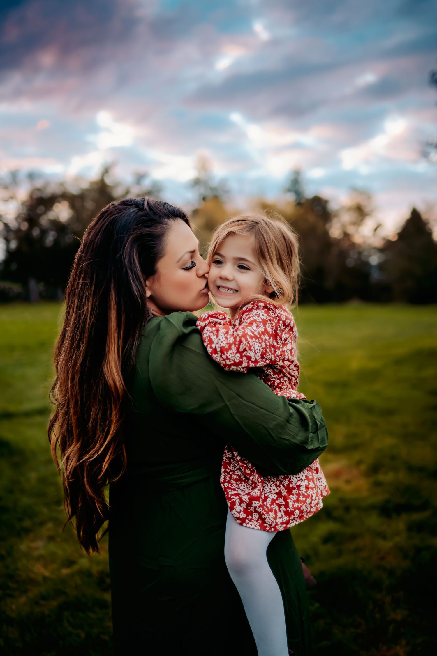 Mother and daughter sharing tender moment outdoors during golden hour.