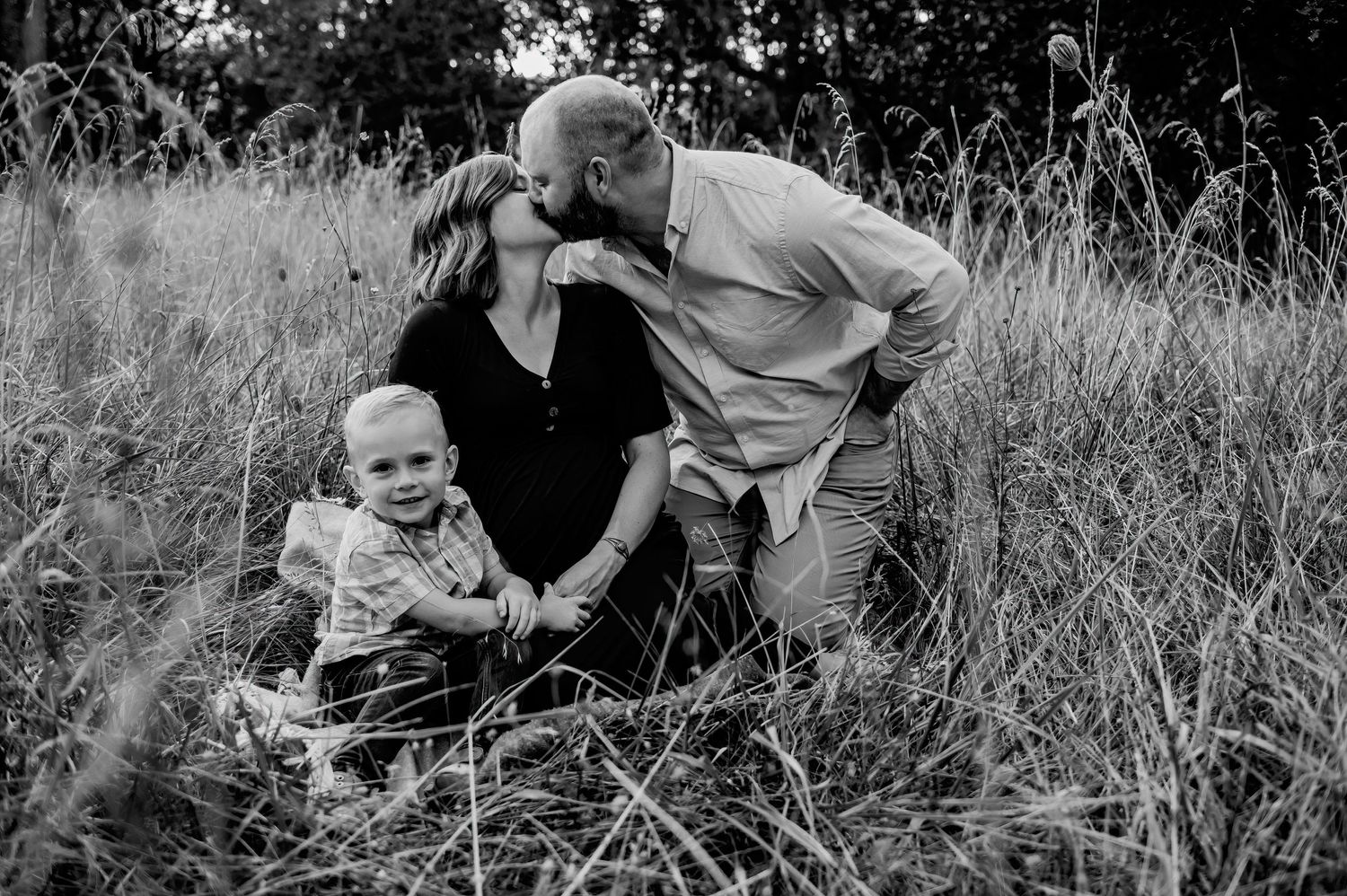 Black and white family portraits taken in a natural outdoor setting with tall grass.