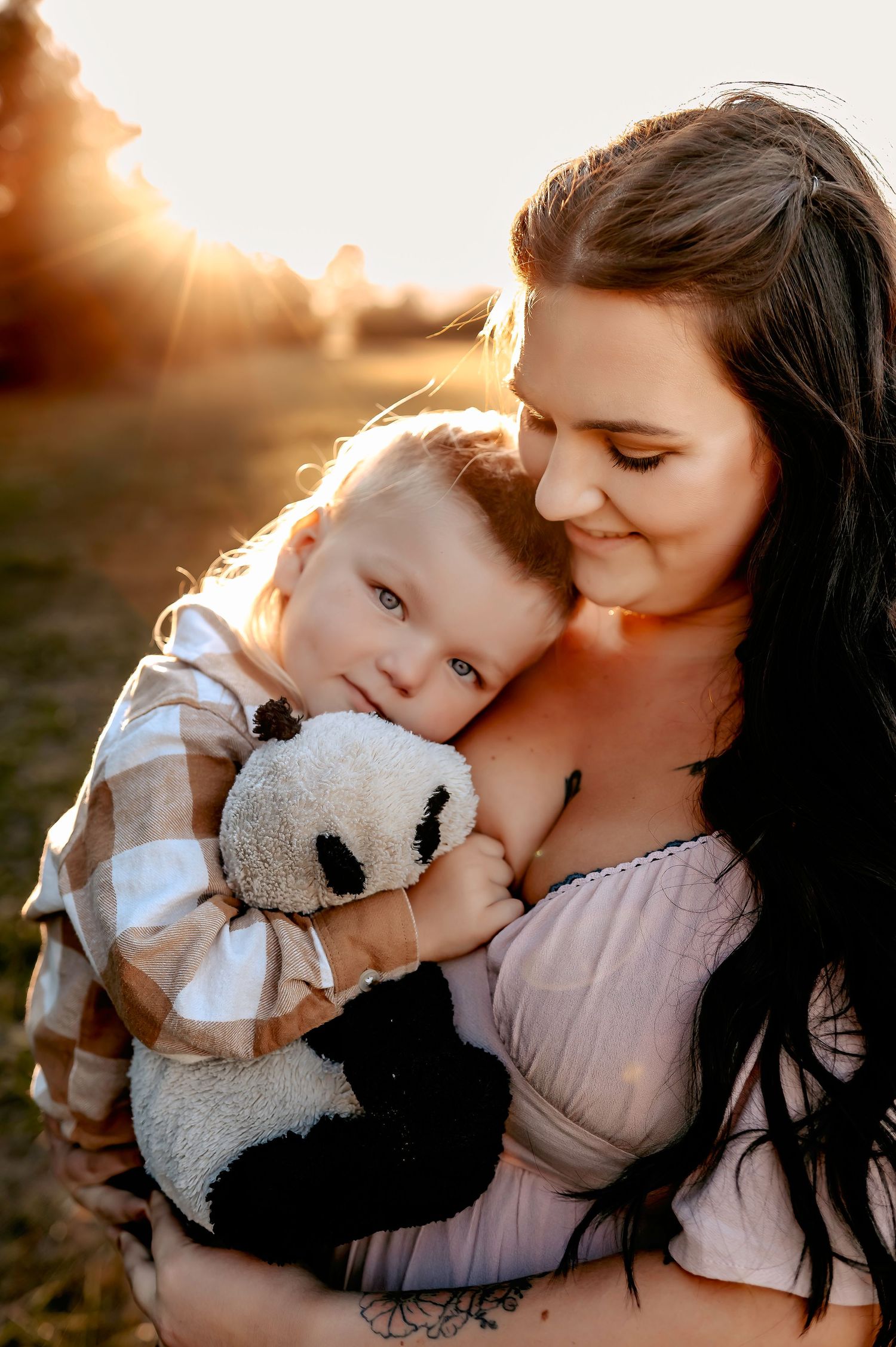 Tender moment between parent and child with stuffed animal during golden hour photoshoot.
