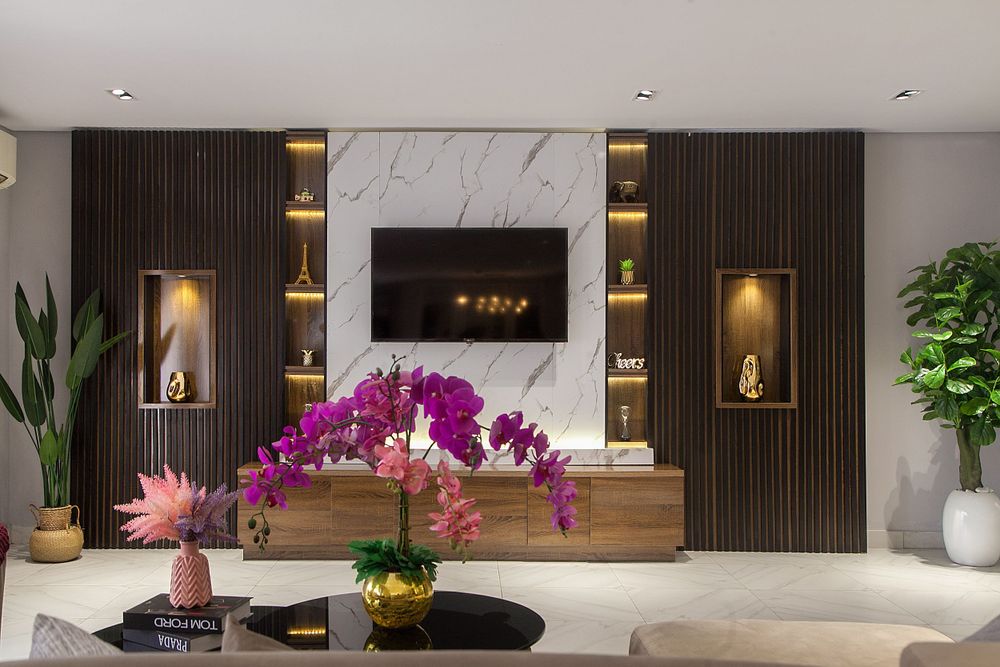 Contemporary living area with dark wood panels, marble walls, and purple orchid accents.