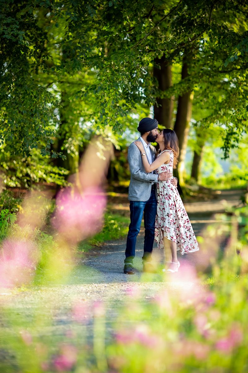 Romantic outdoor photo in a lush green park with pink flowers in foreground.