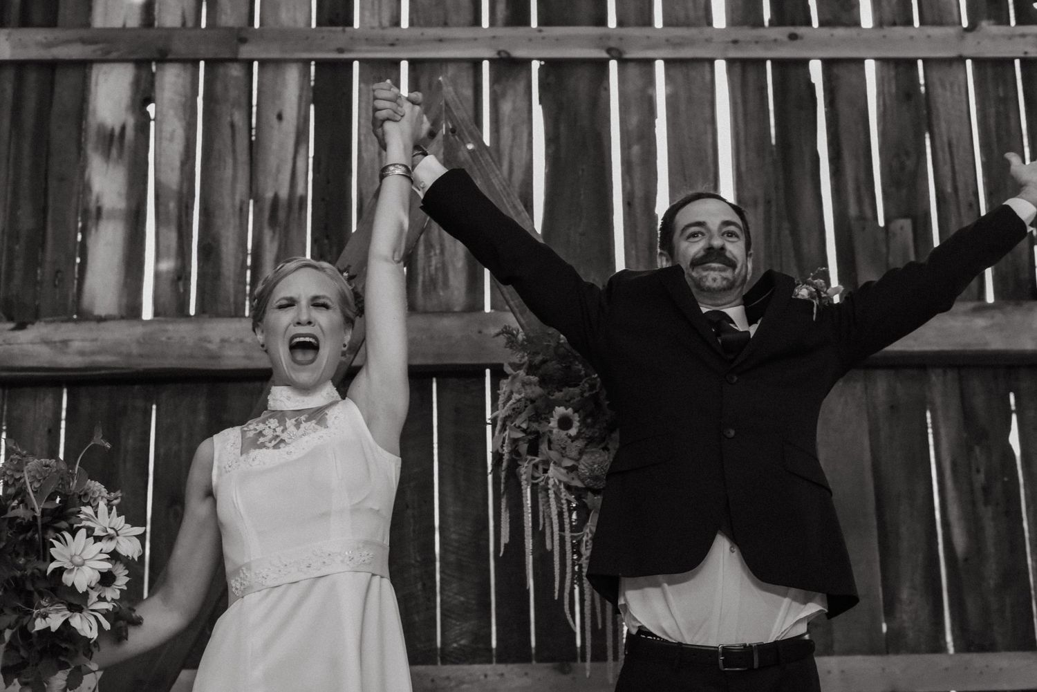 An enthusiastic celebration moment with raised arms in front of wooden barn walls.