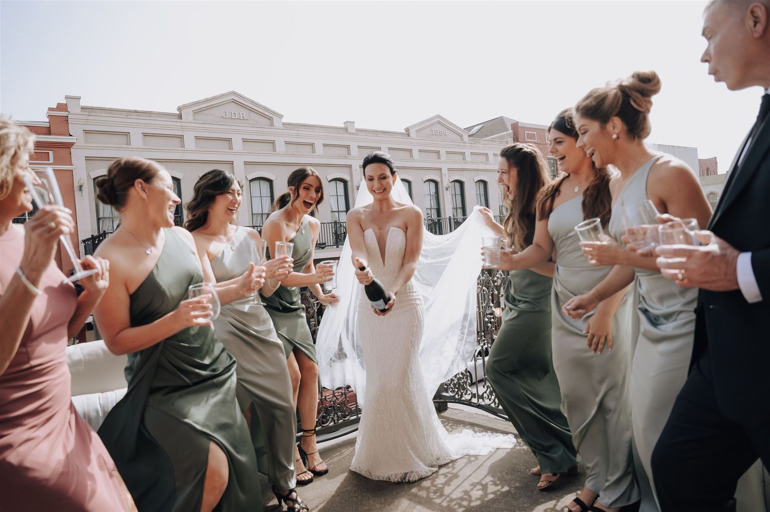 Wedding celebration on urban rooftop with bridal party in sage green dresses.