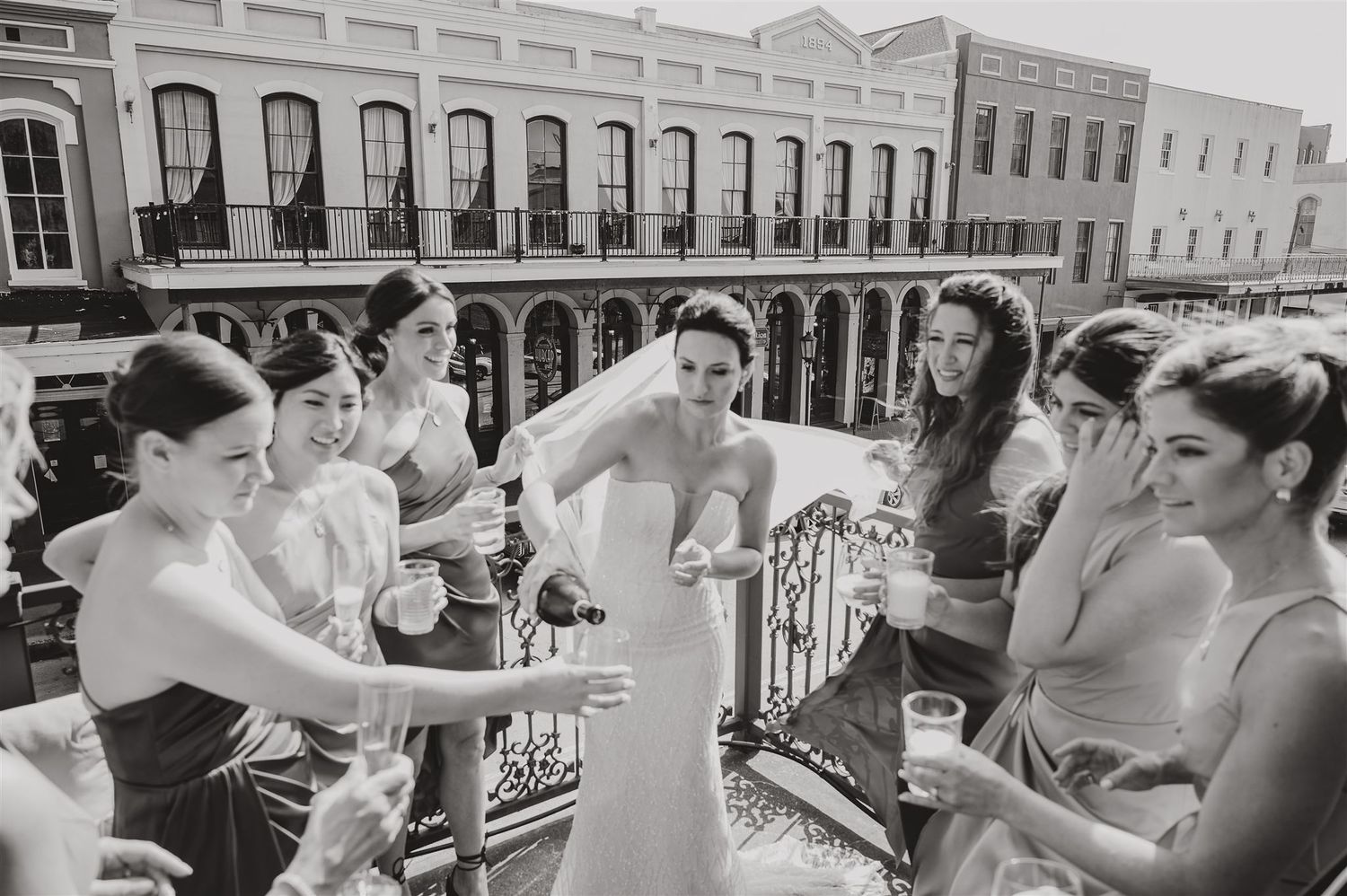 Black and white photo of wedding celebration on historic building balcony.