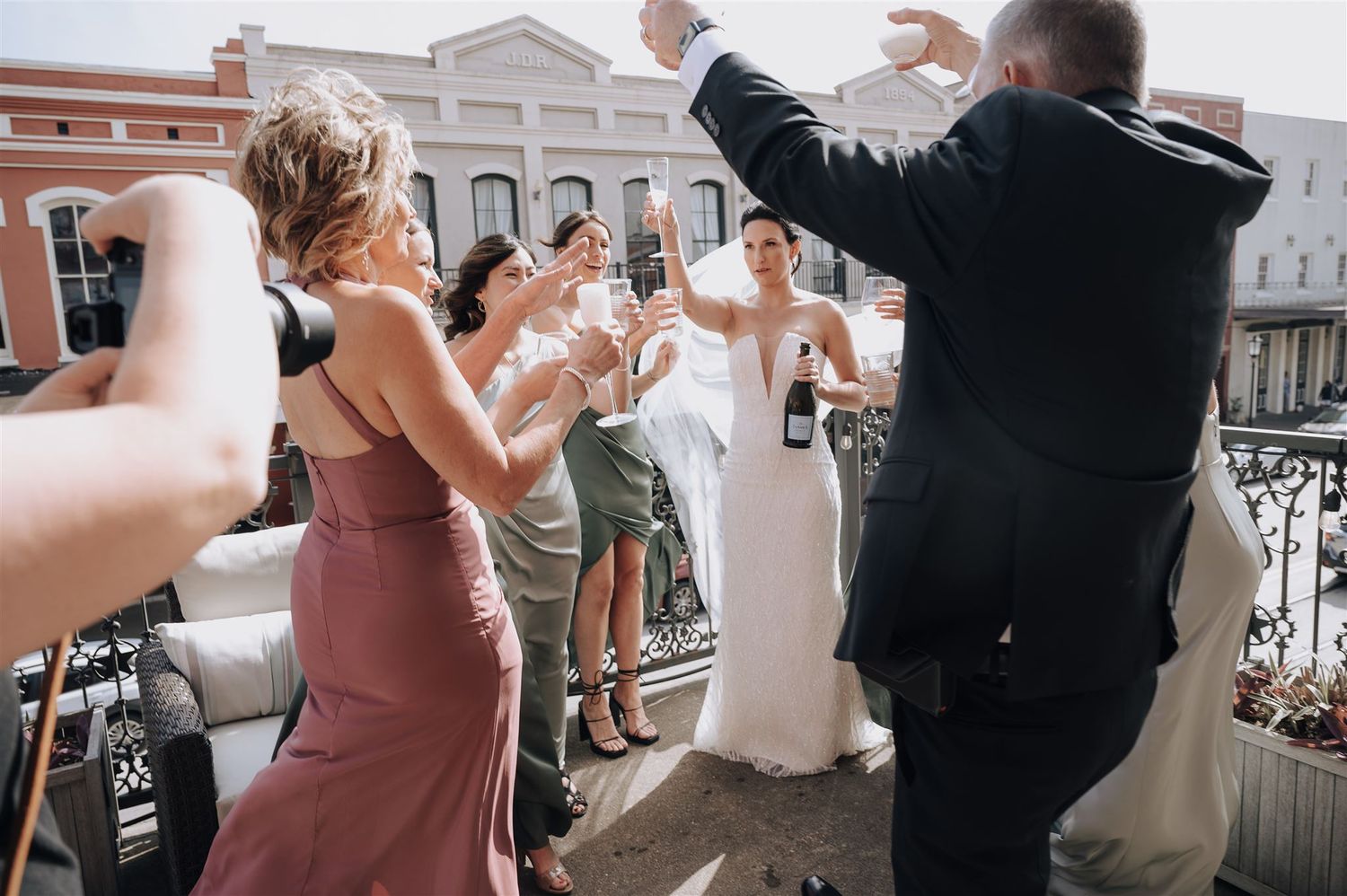 Celebratory champagne toast on vintage balcony during wedding festivities.