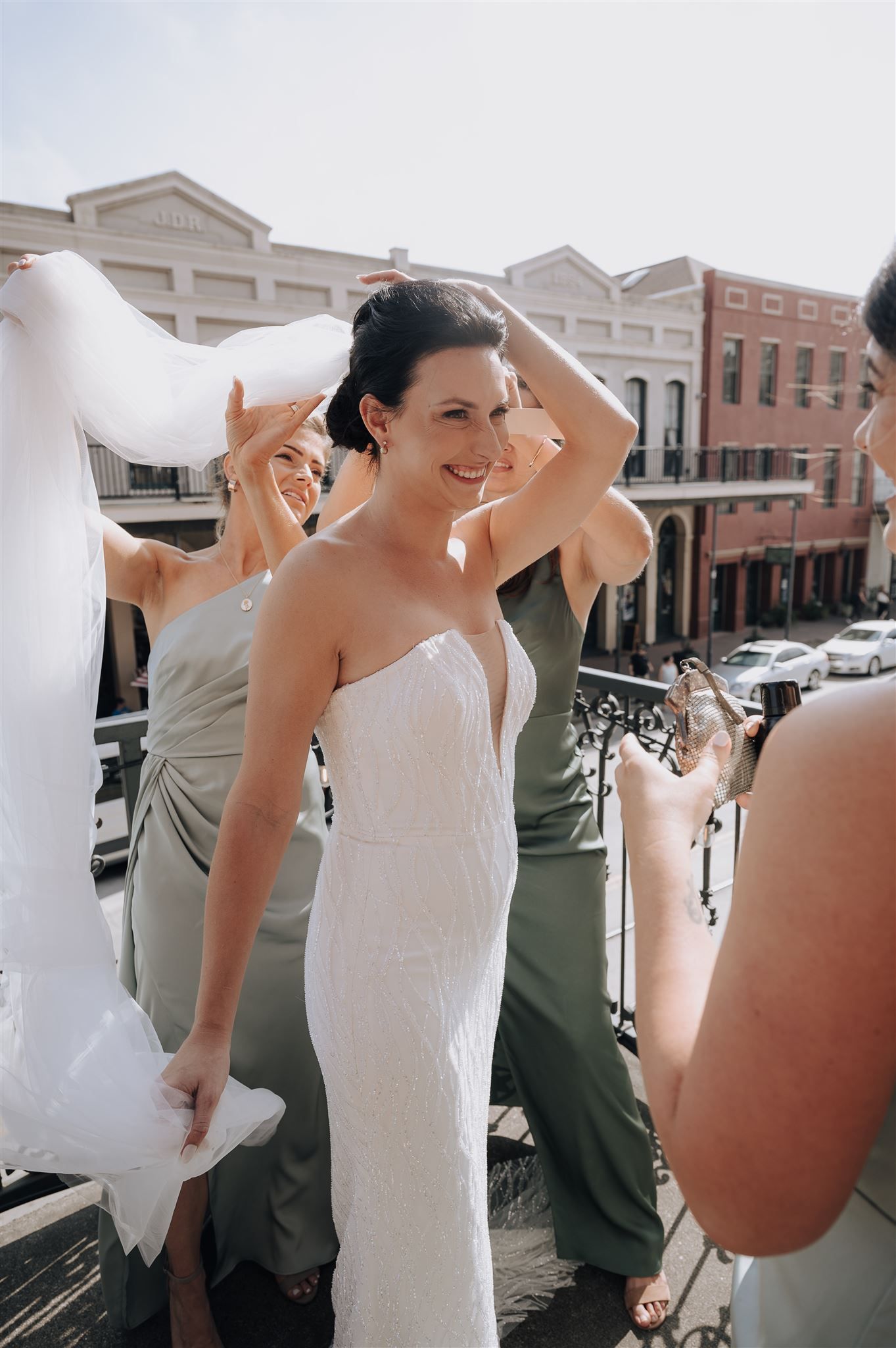 Wedding celebration on ornate balcony overlooking historic downtown buildings.