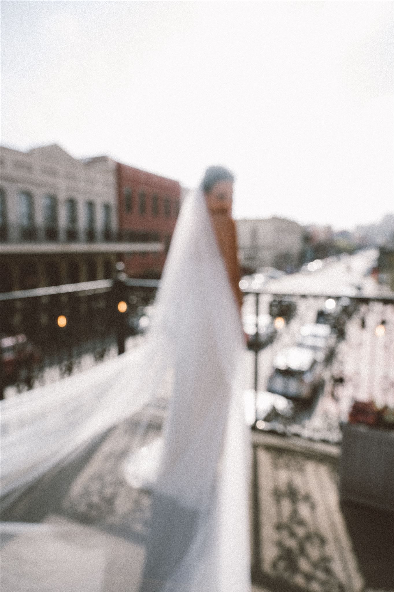 Blurred urban street view through white fabric with historic buildings in background.