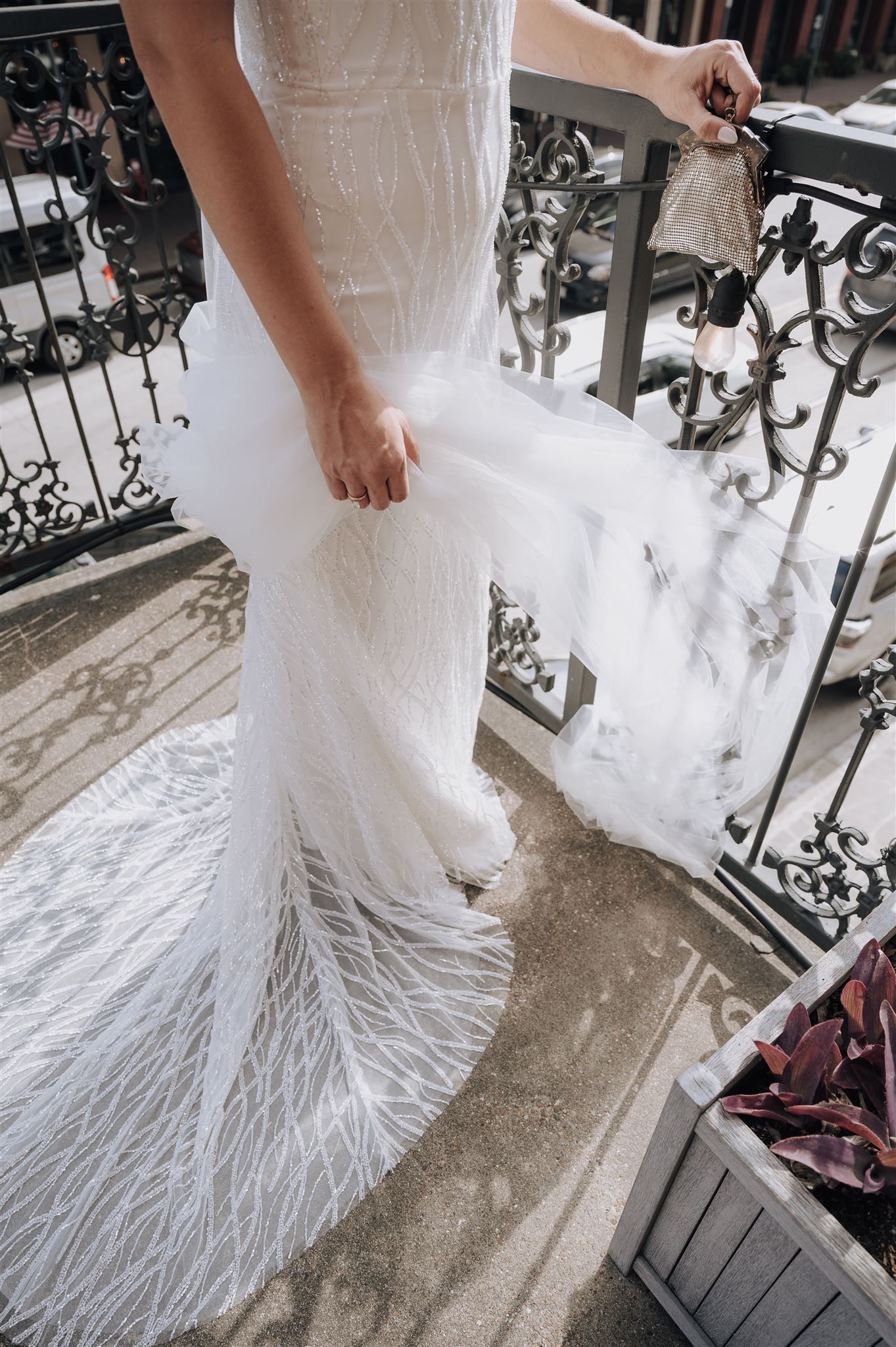 Close-up of a wedding dress with feathered hem detail on an ornate balcony.