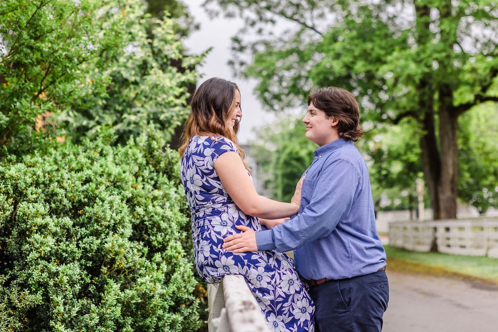 Couple shares intimate moment in garden setting with lush green background.