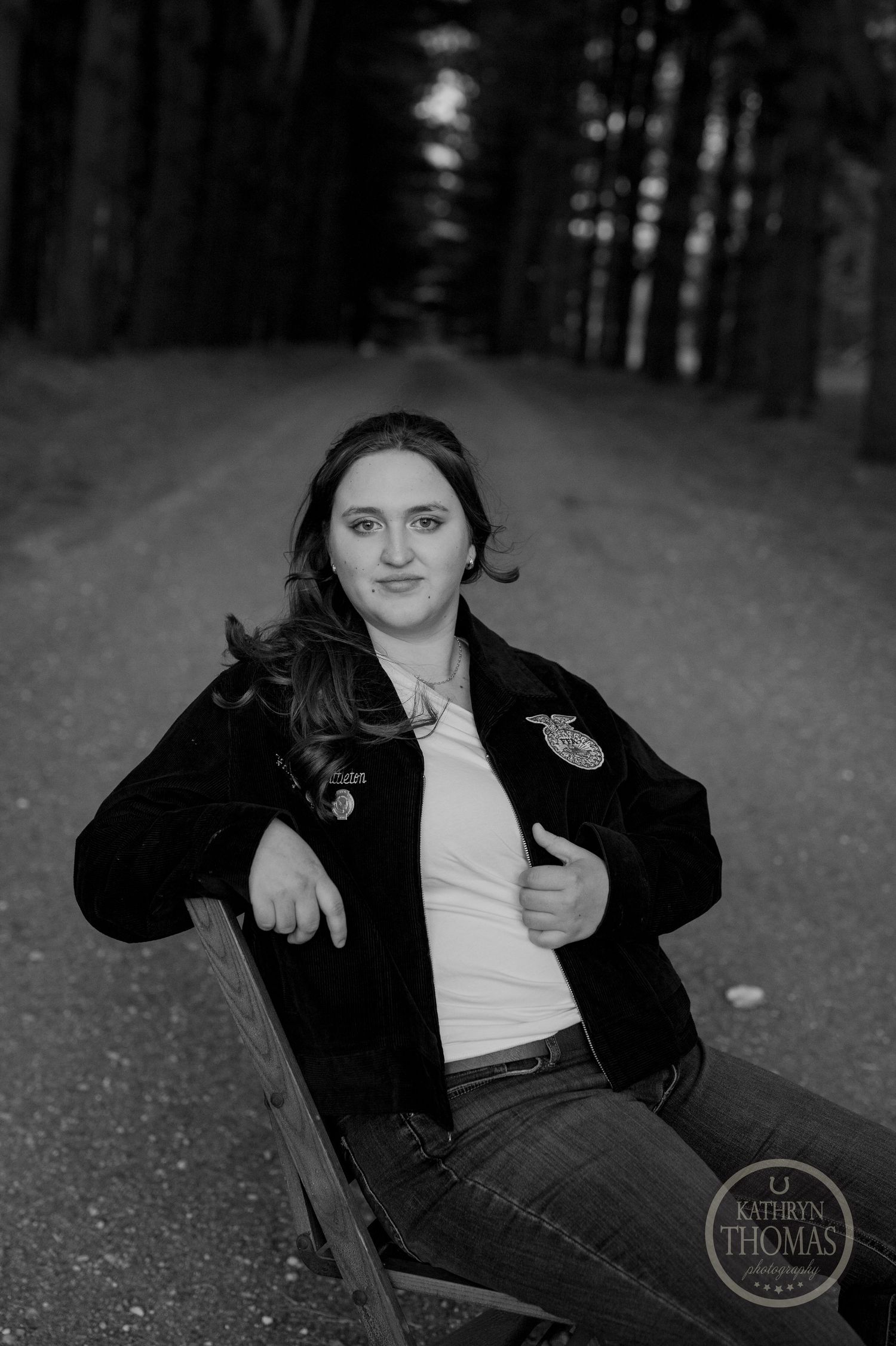 A black and white portrait shows a relaxed pose on a chair in a forest setting.
