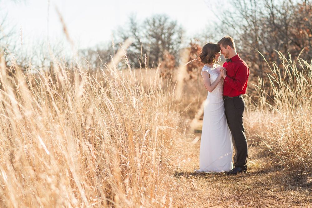 Bride and groom embracing in a golden field of tall grass during an outdoor fall wedding photo session.