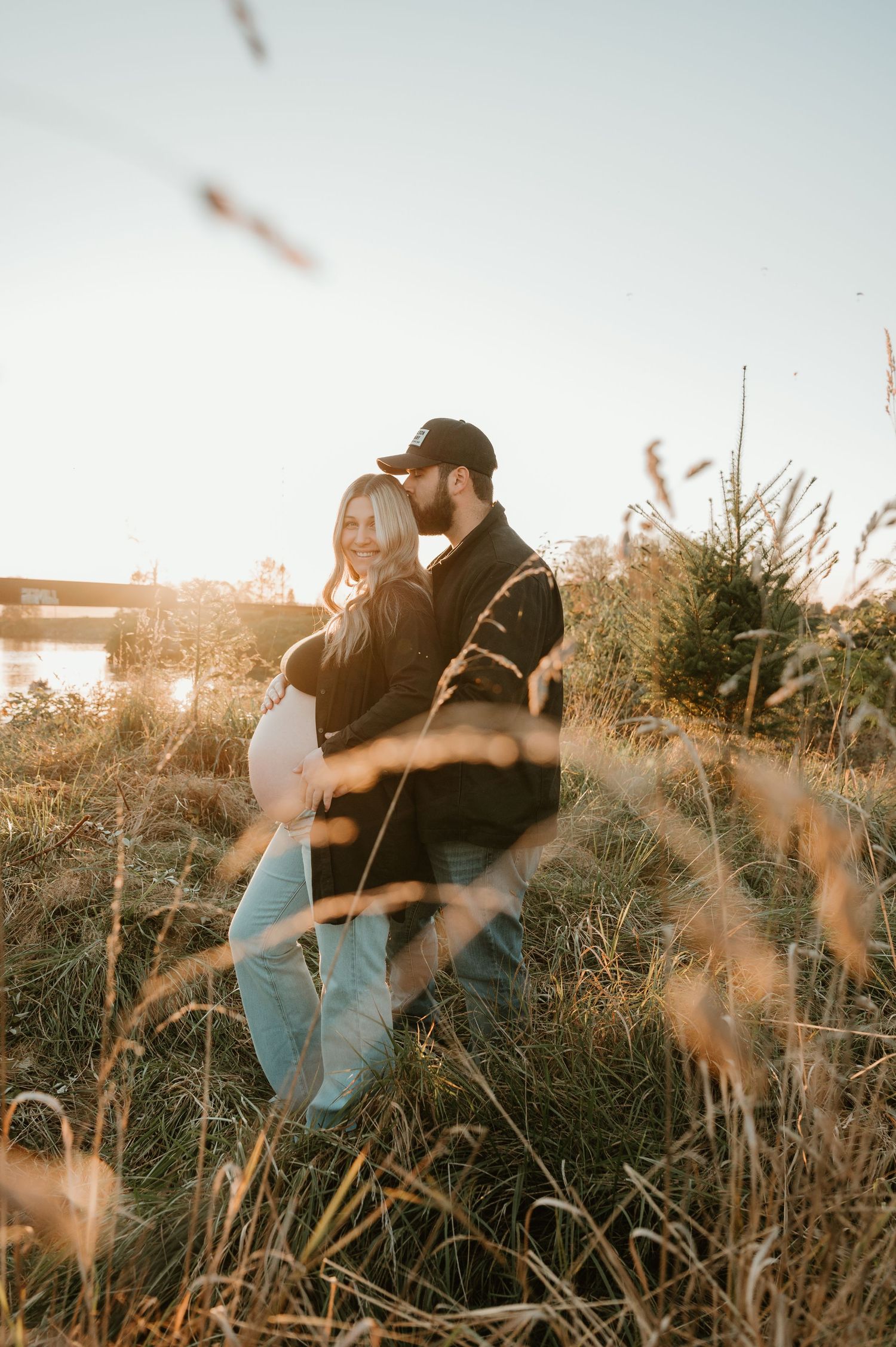 Sunset engagement session in tall grass field with warm backlighting.