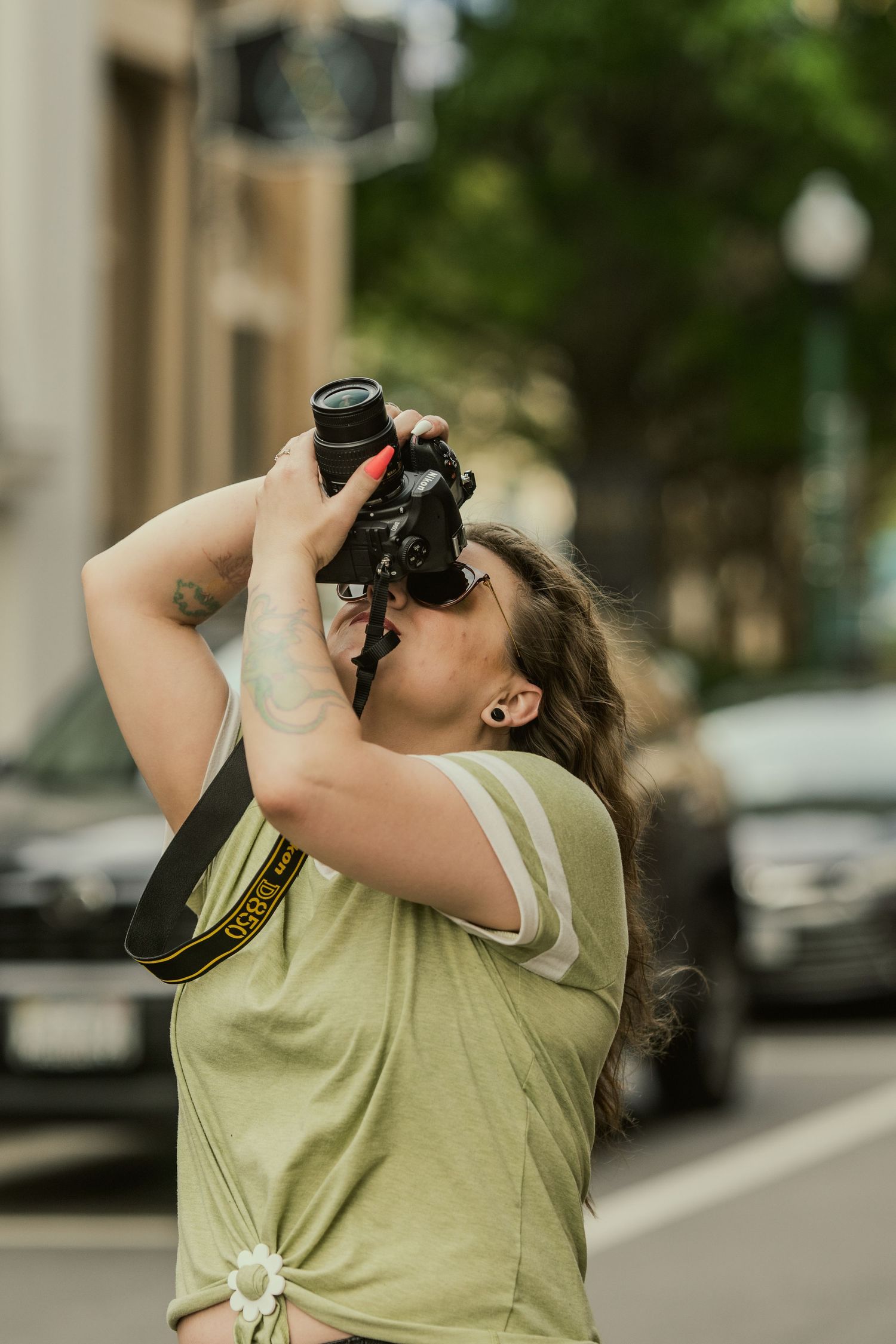 Photographer in olive green shirt taking upward angle shot with professional camera.