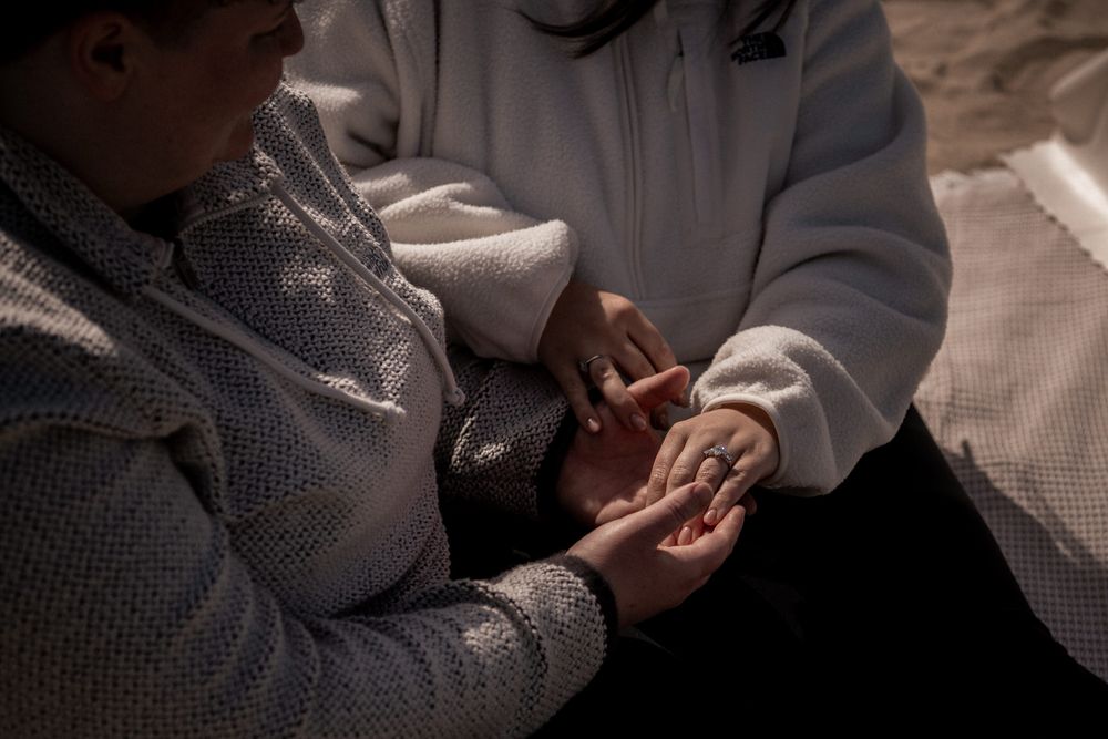 Close-up of two people holding hands tenderly outdoors, sharing an intimate moment of connection and care.