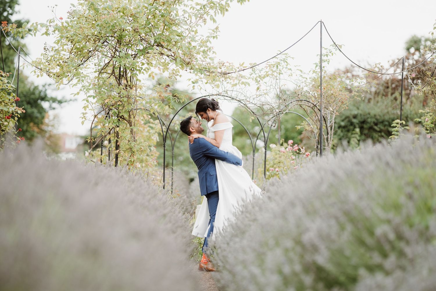 indian hindu couple sharing cute candid moment in lavender field in white wedding dress