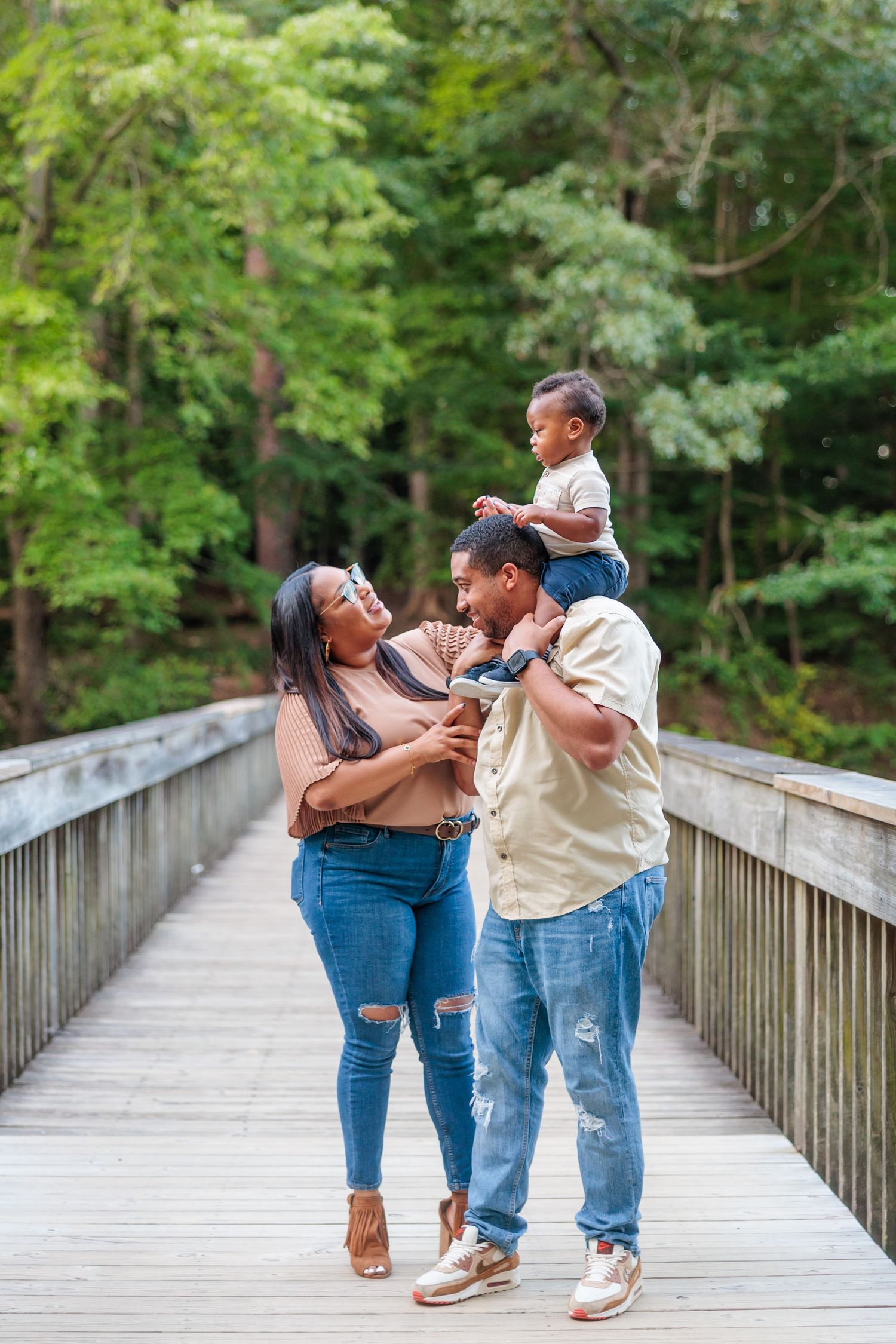 Happy family sharing a playful moment together on wooden boardwalk surrounded by lush forest.