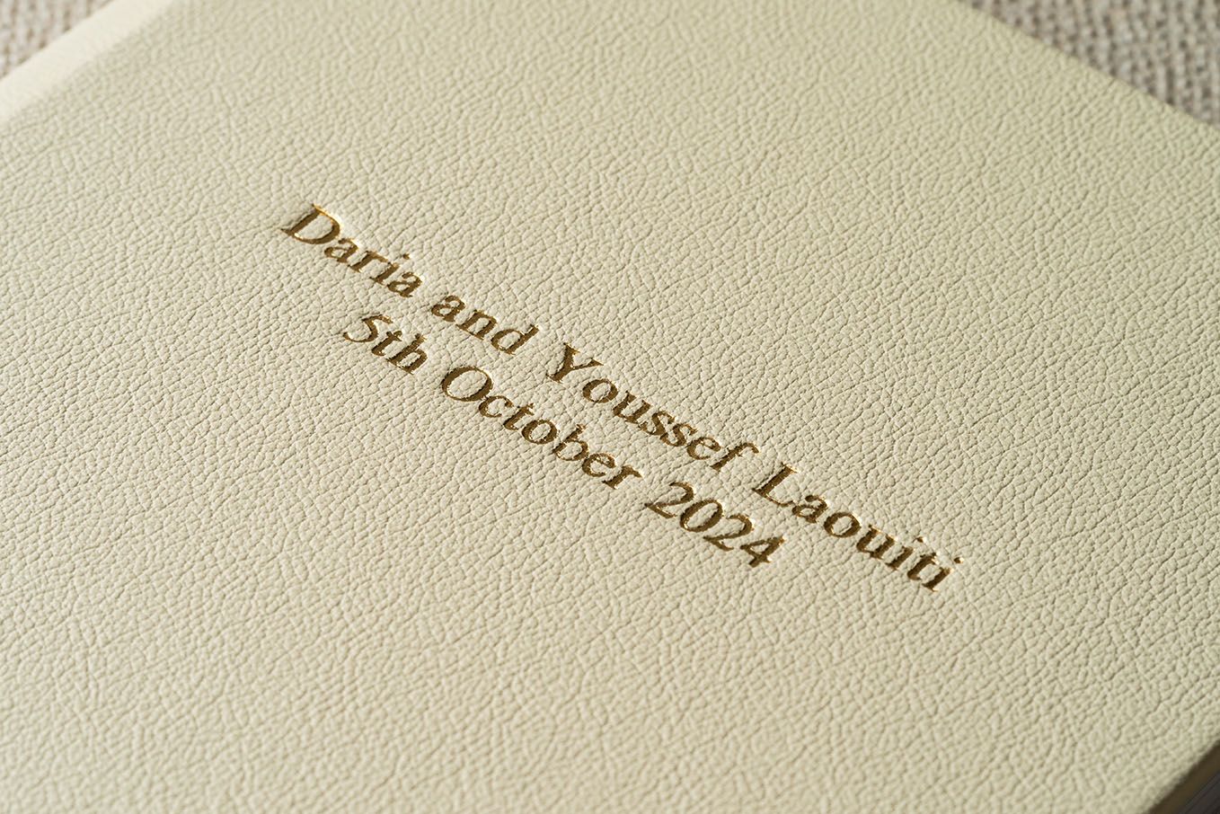 Blue leather wedding album with golden text showing names Christina and Stefanos embossed on the cover.