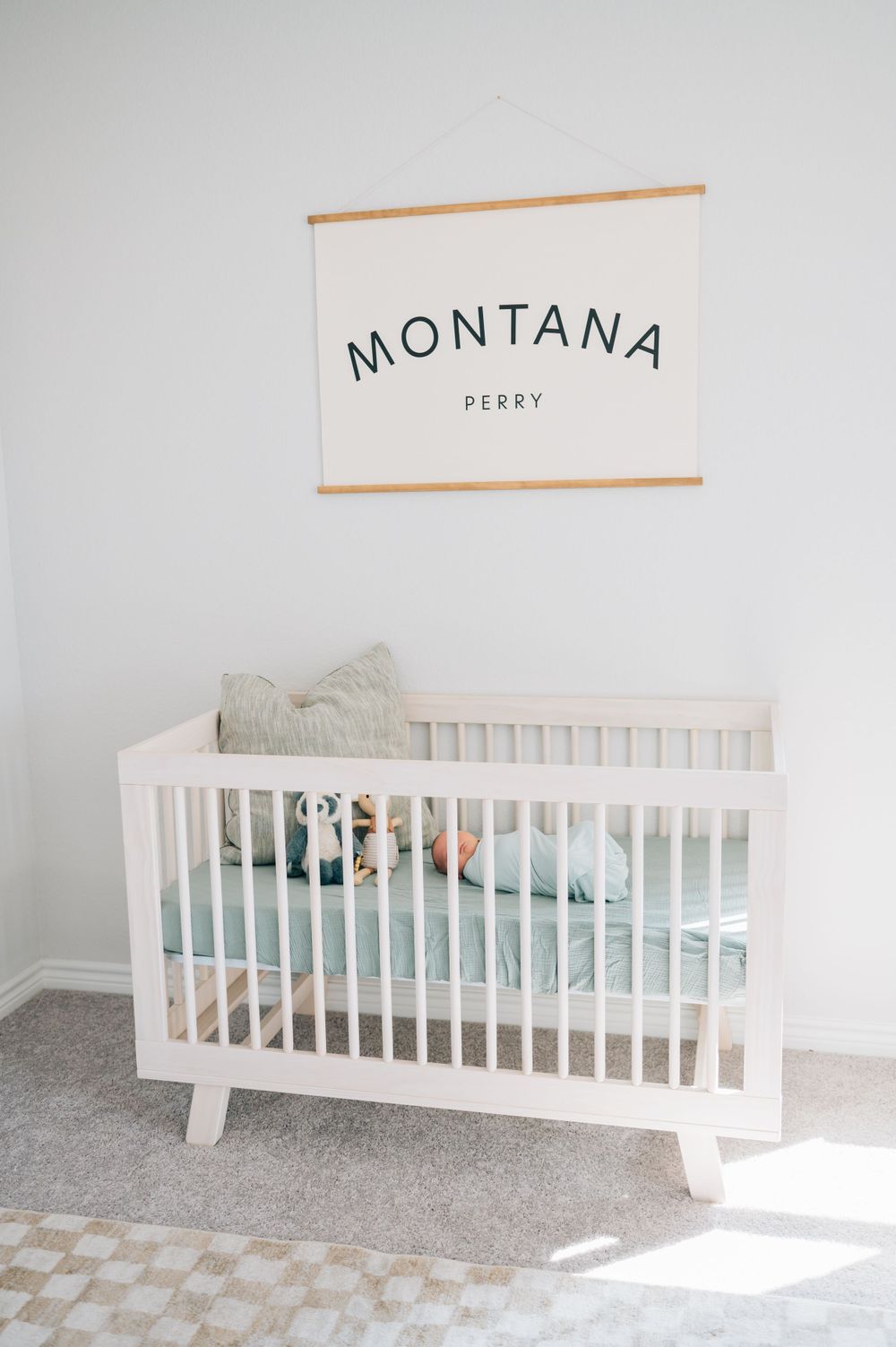 Modern white nursery with minimalist crib and Montana wall art in natural lighting.