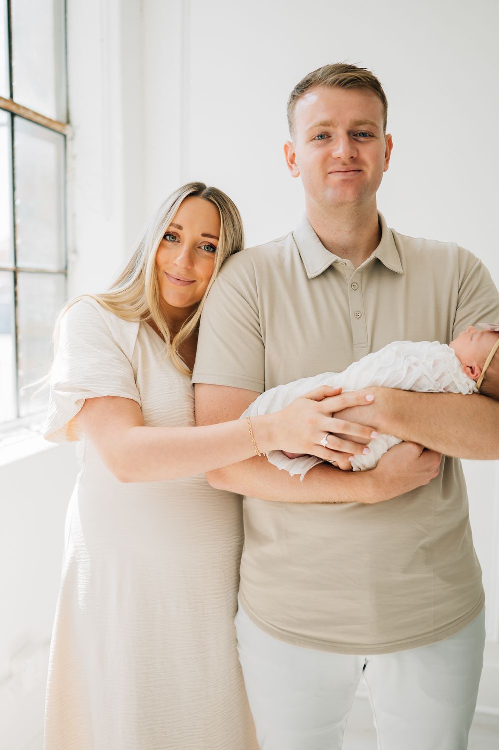 Modern family portrait in neutral colors against bright white interior setting.