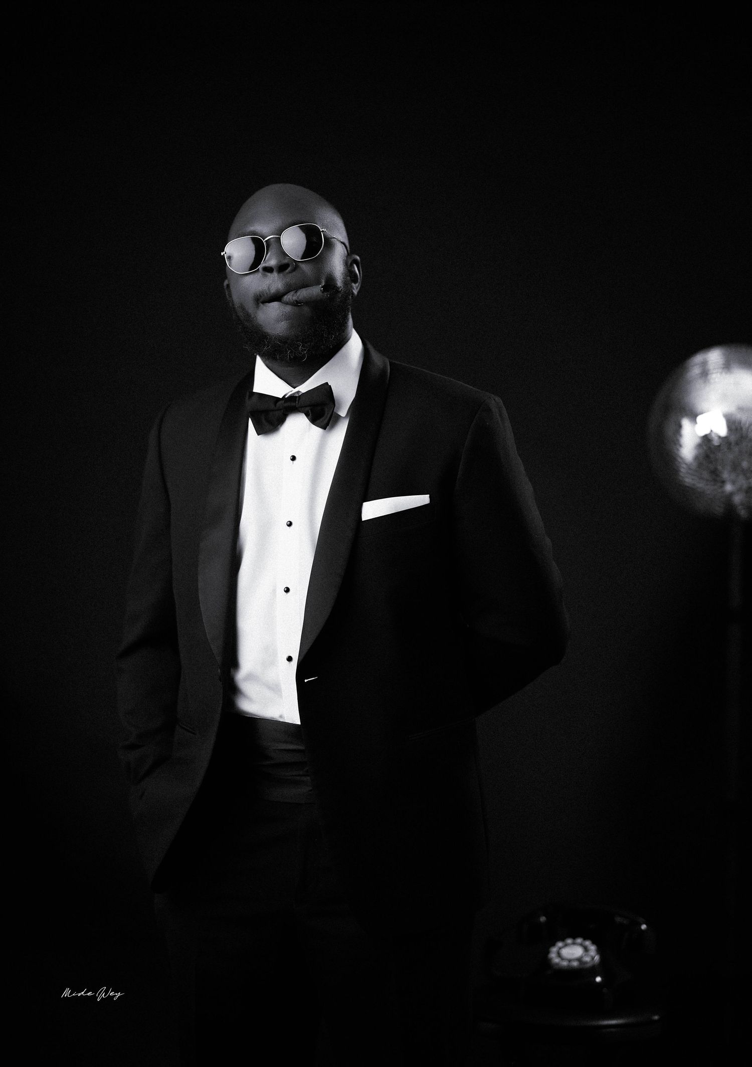 A dramatic black and white portrait series of a person in a classic tuxedo with bow tie against a dark background.