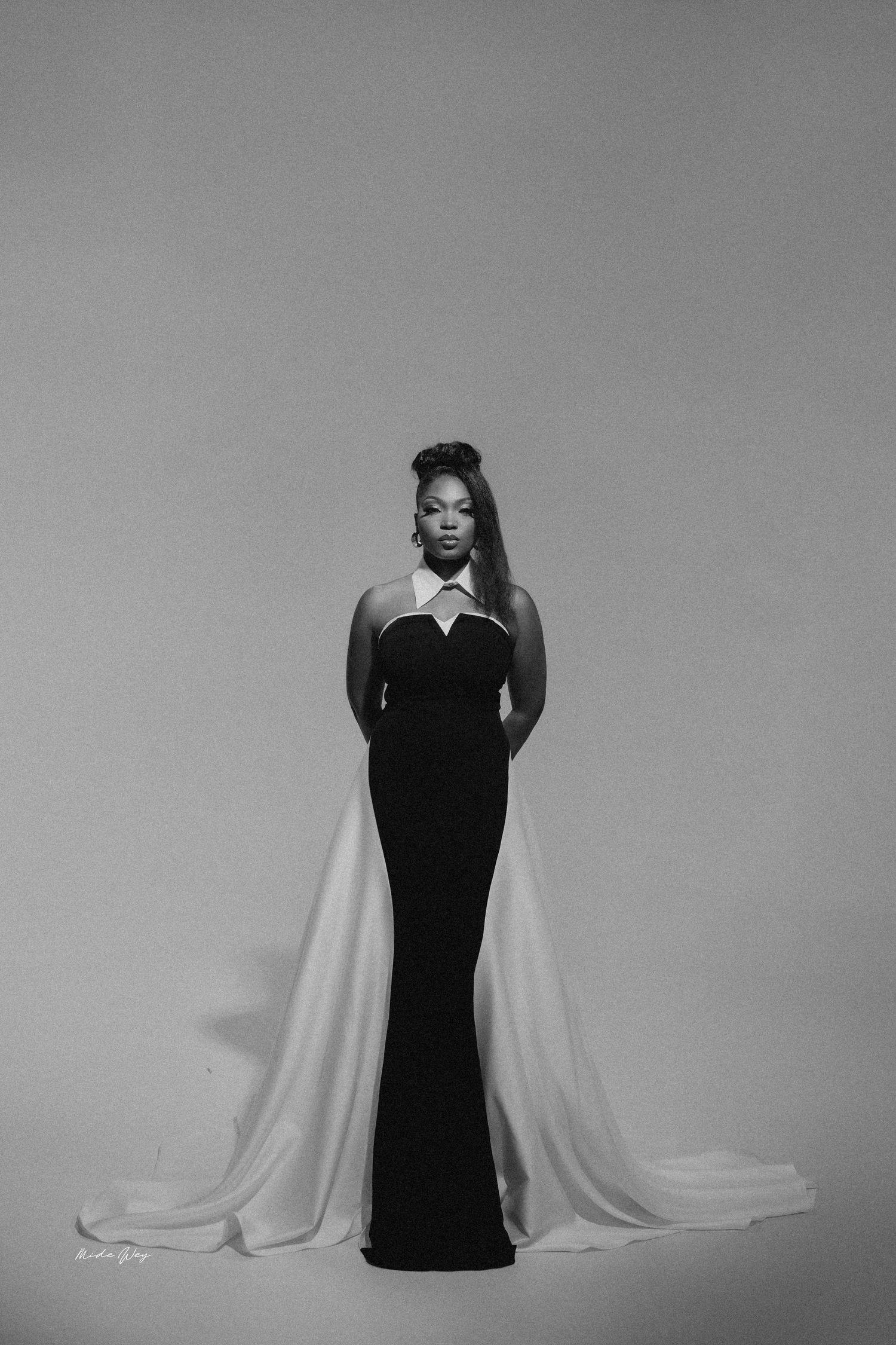 A black and white photo sequence showing a figure in a dark dress against a light background performing expressive poses.