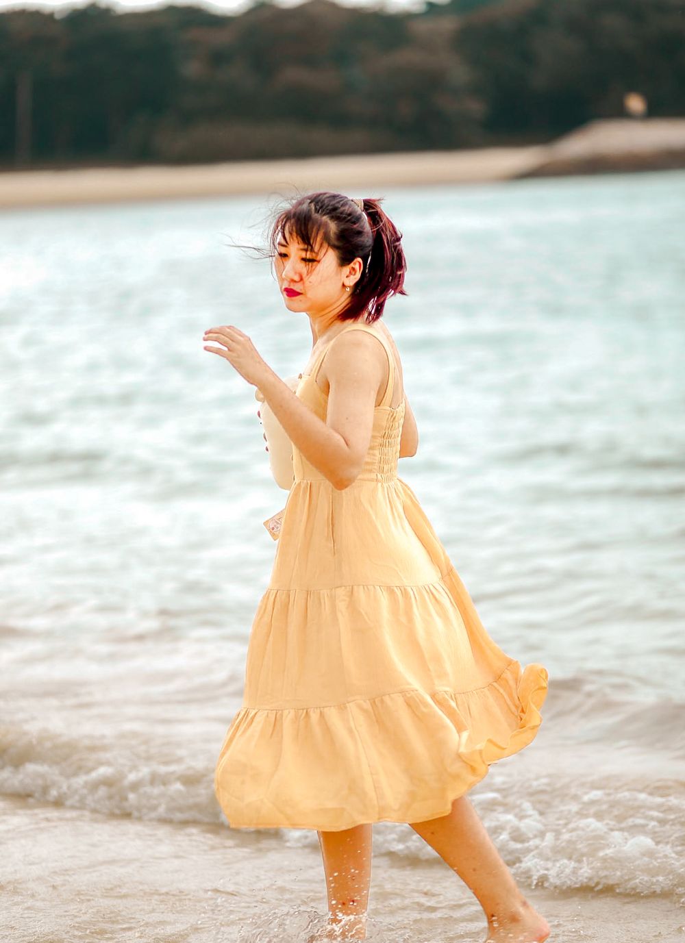 Woman in a flowy dress twirling in an open space, running freely at the beach with sunlight streaming through in Singapore photoshoot