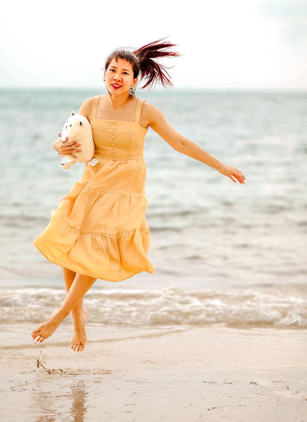 Woman in a flowy dress twirling in an open space, running freely at the beach with sunlight streaming through in Singapore photoshoot