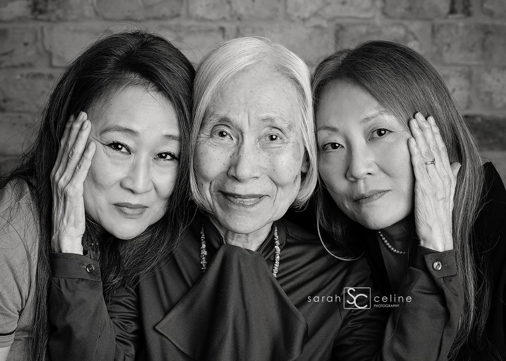 Black and white portrait of generations of women touching faces together.