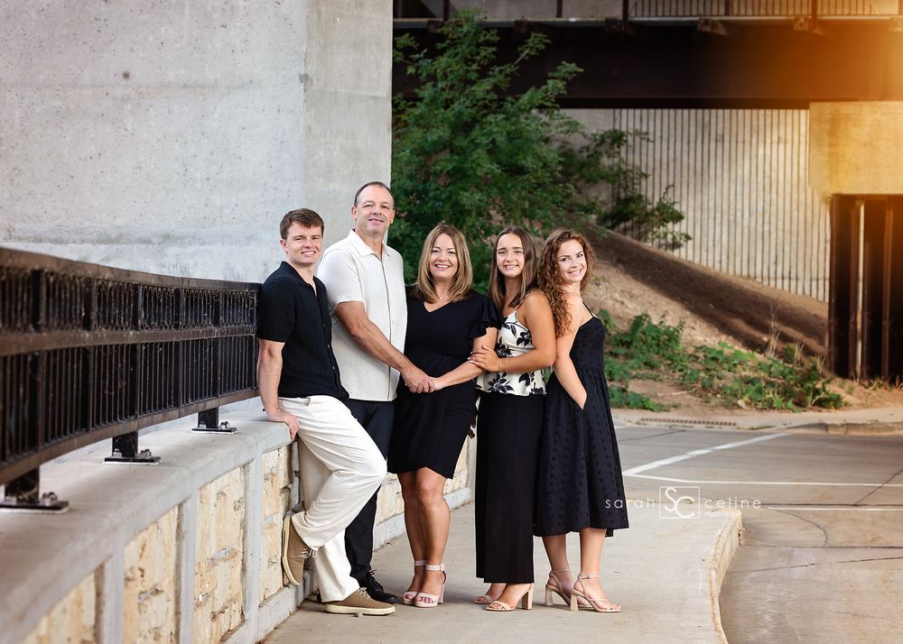 A series of black and white family portraits taken outdoors against a stone wall and wood paneling background.
