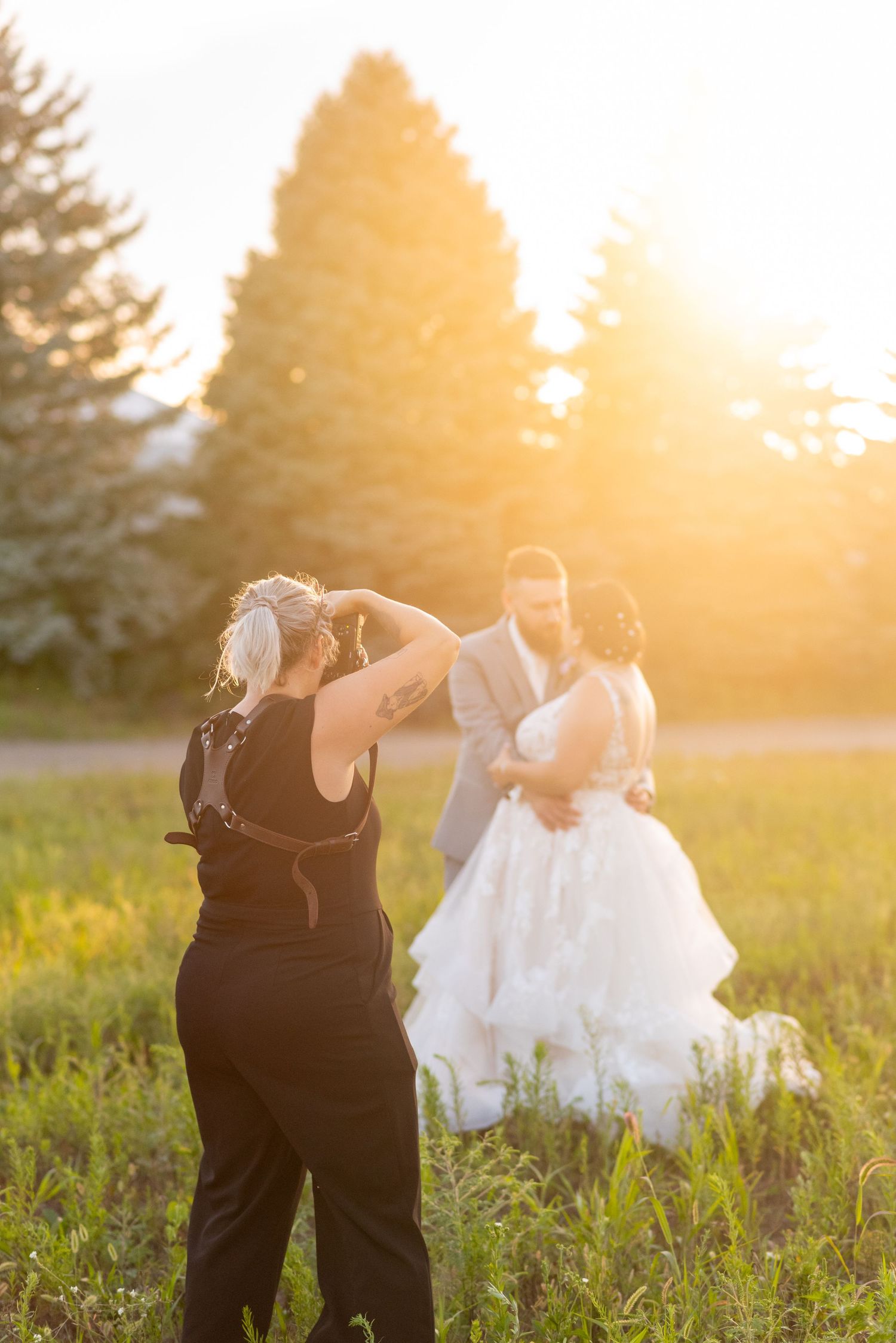 Silhouettes of wedding party dancing in golden sunset light in grassy field in Strathroy.