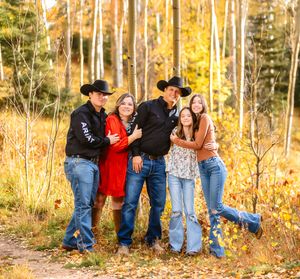 People in casual western attire lean on each other in a scenic autumn forest with golden aspen trees.