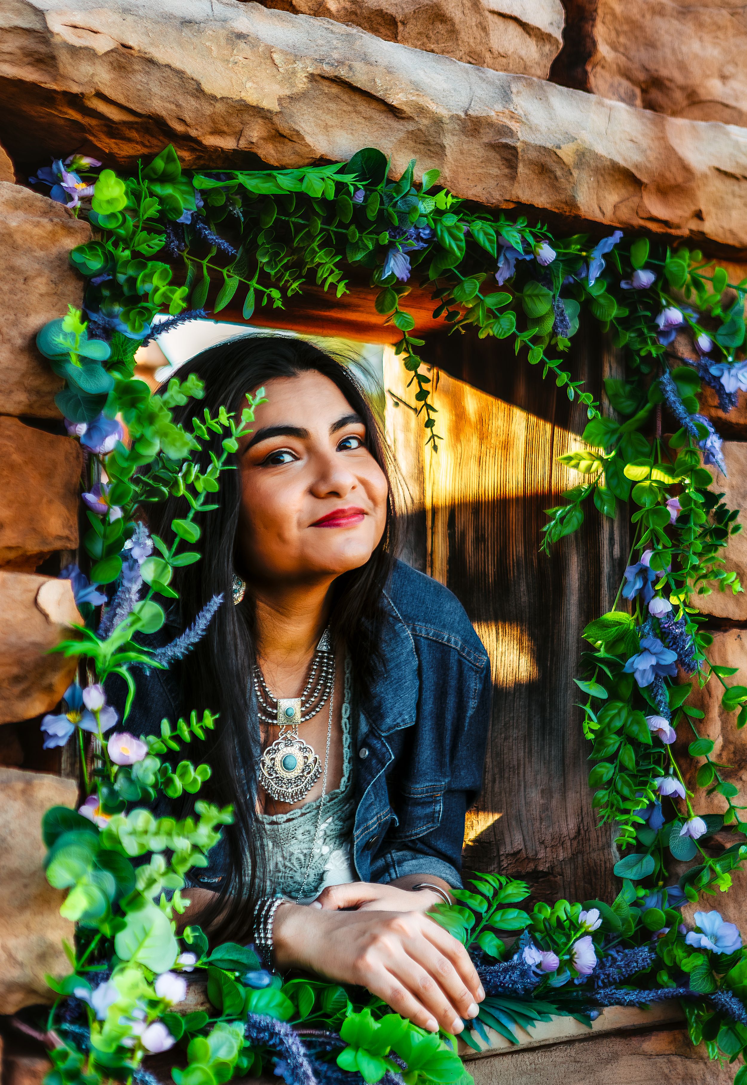 Artistic portrait sequence in rustic setting with lush green vines, denim jacket and statement necklace against stone wall.