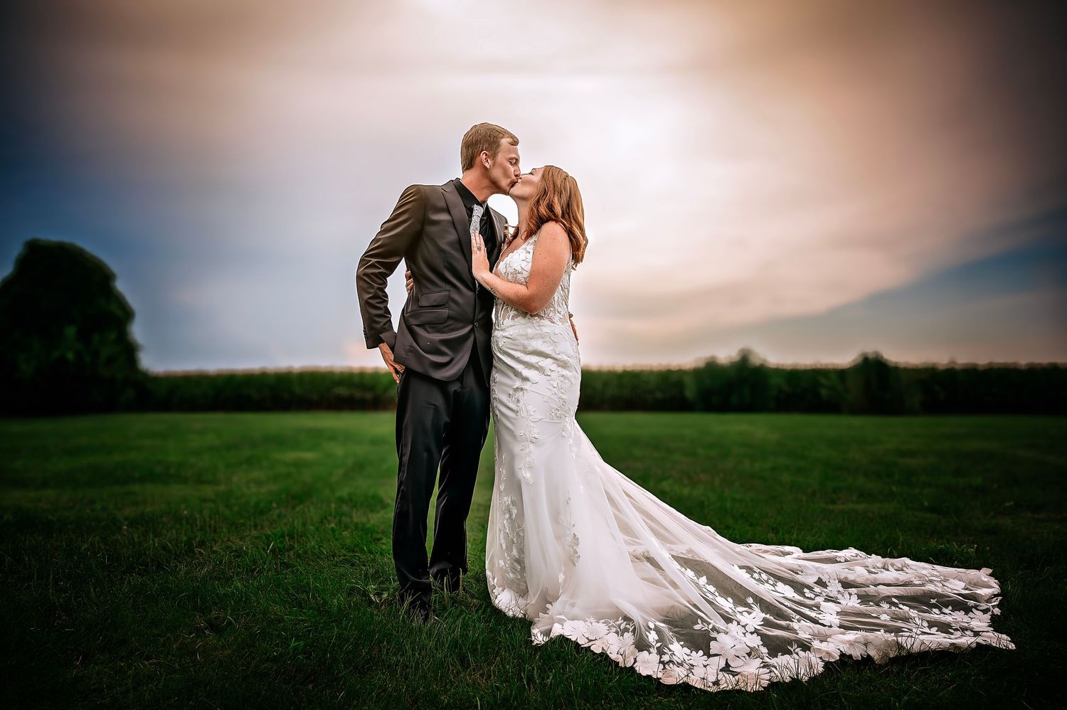 An outdoor wedding ceremony under wooden arches beside a lake on a sunny day.